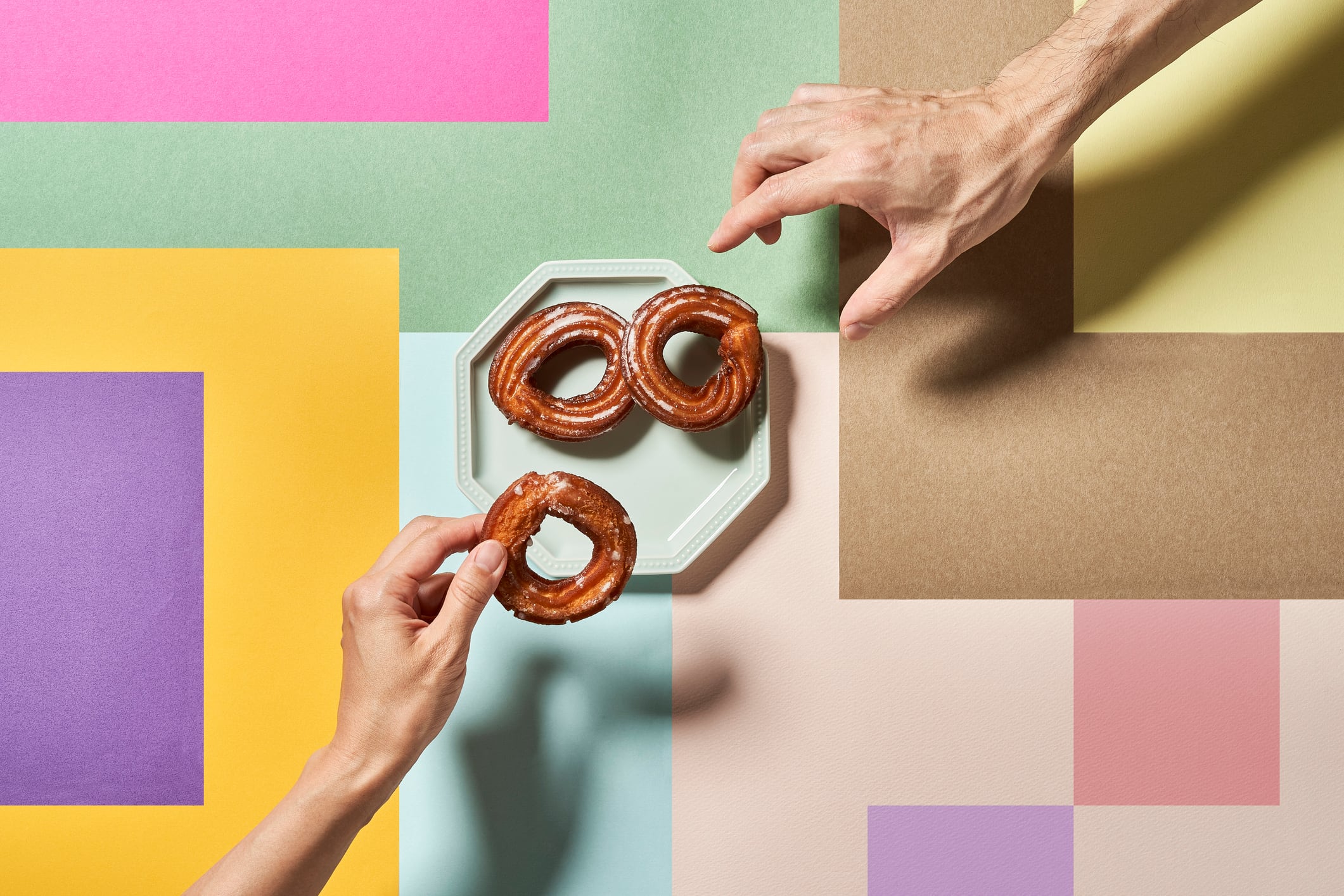 Hands reaching for churros against a multicoloured background