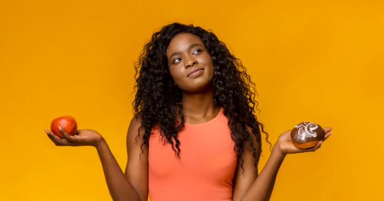 Young-woman-deciding-apple-or-donut-Prostock-Studio.jpg