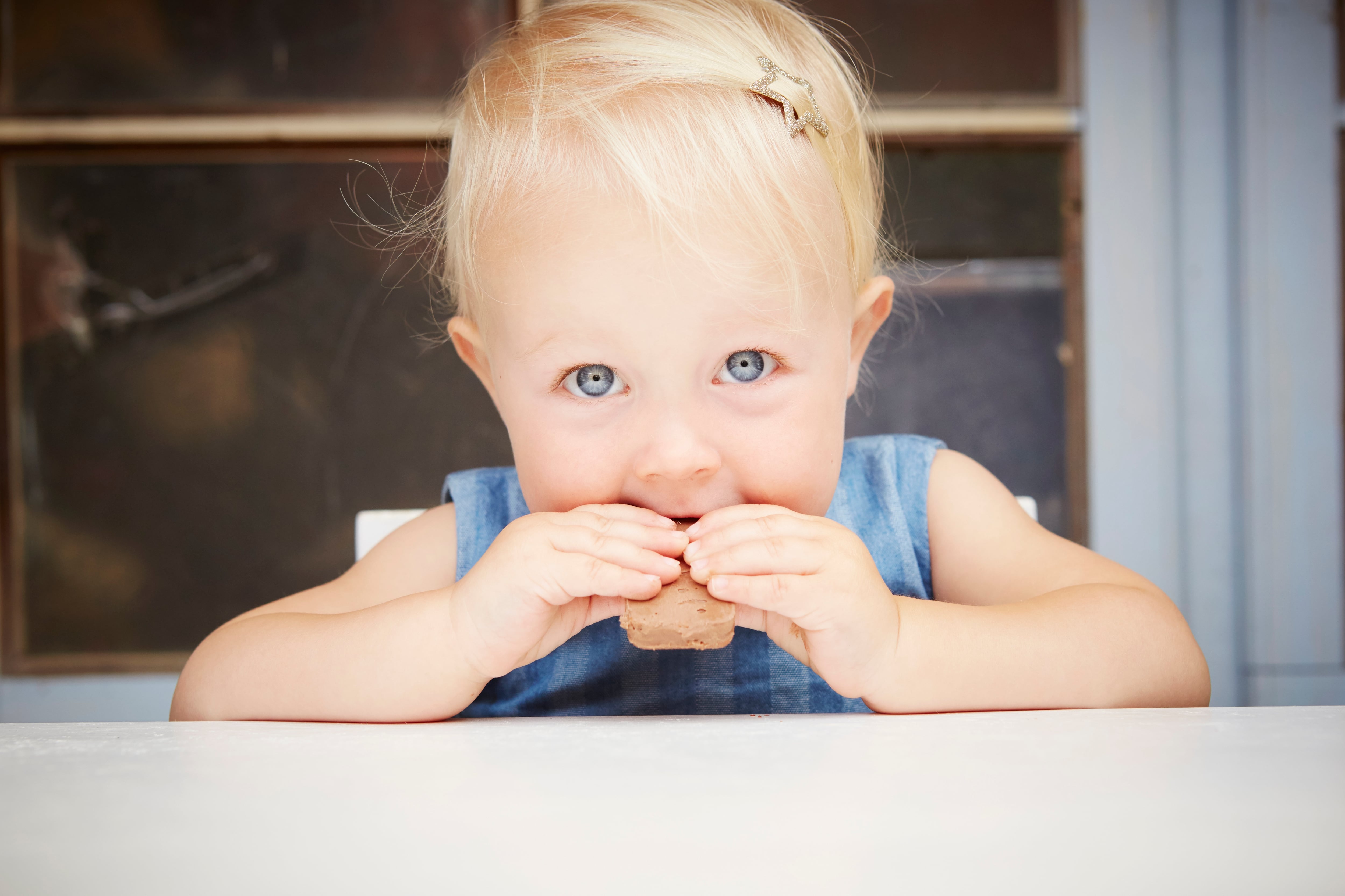 Baby girl eating a chocolate biscuit