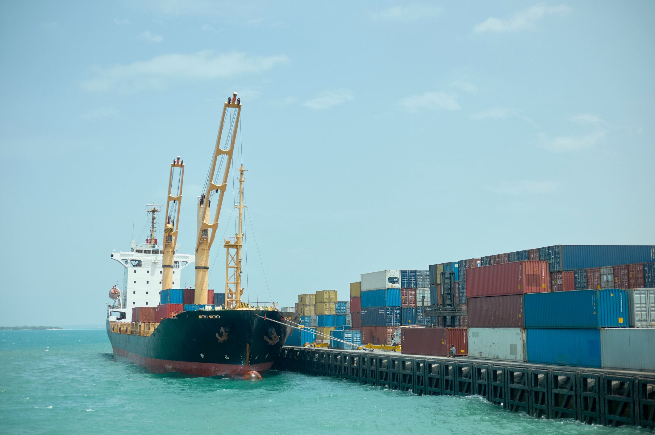 Cargo ship docked at a bustling port with stacked colorful shipping containers. Tanzania, Zanzibar