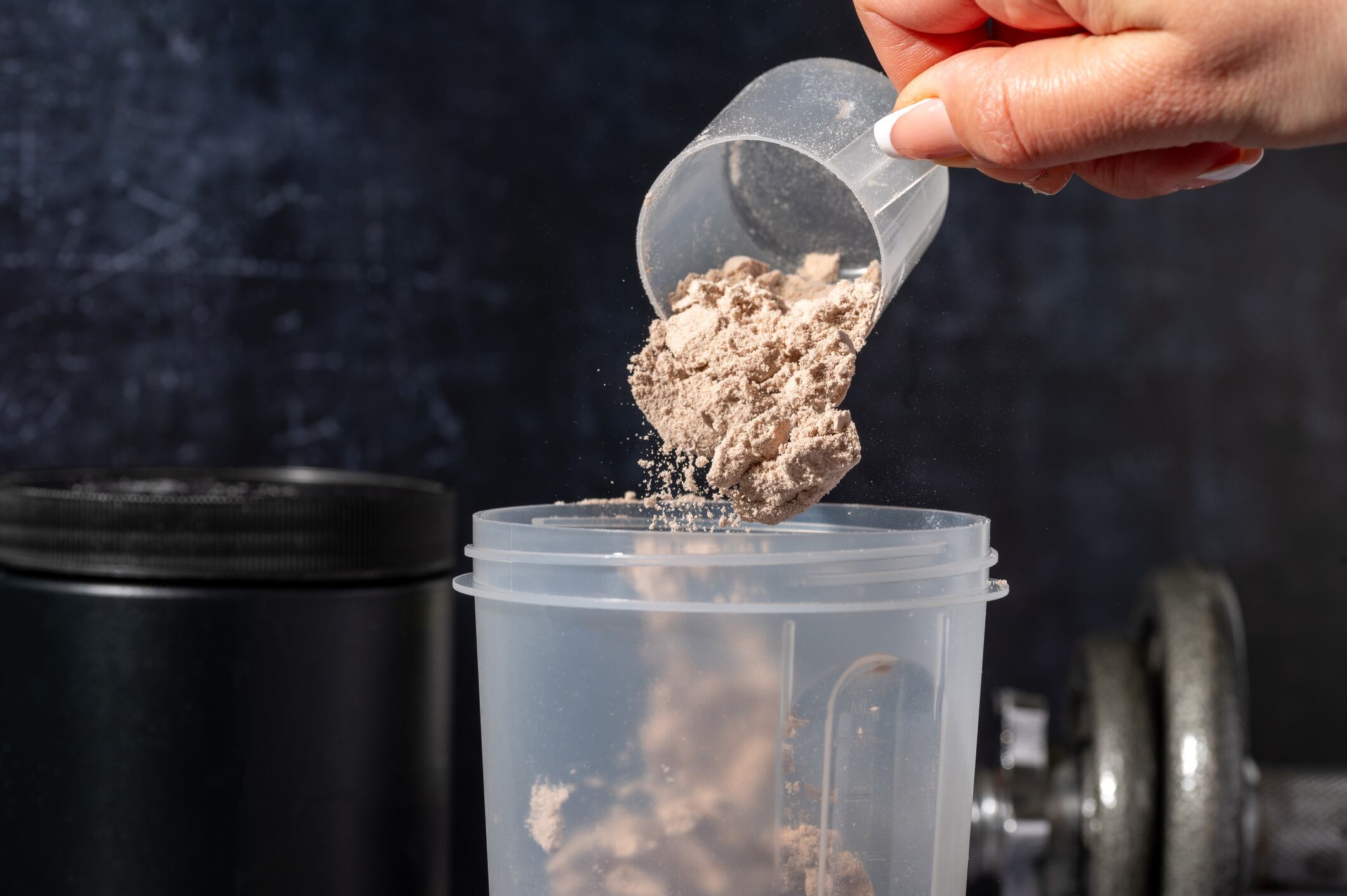Pouring Chocolate protein powder in a shaker. Food supplements. Dark background. Bodybuilding, fitness, gym