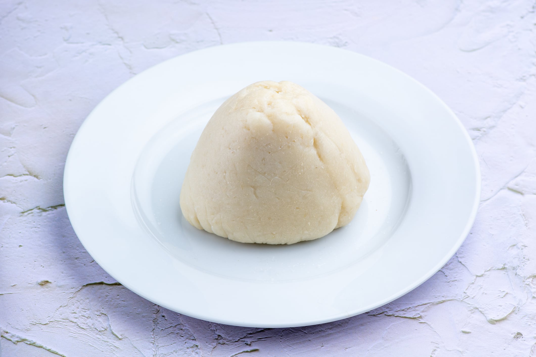 An image of fufu / pounded yam isolated on a white, ceramic plate