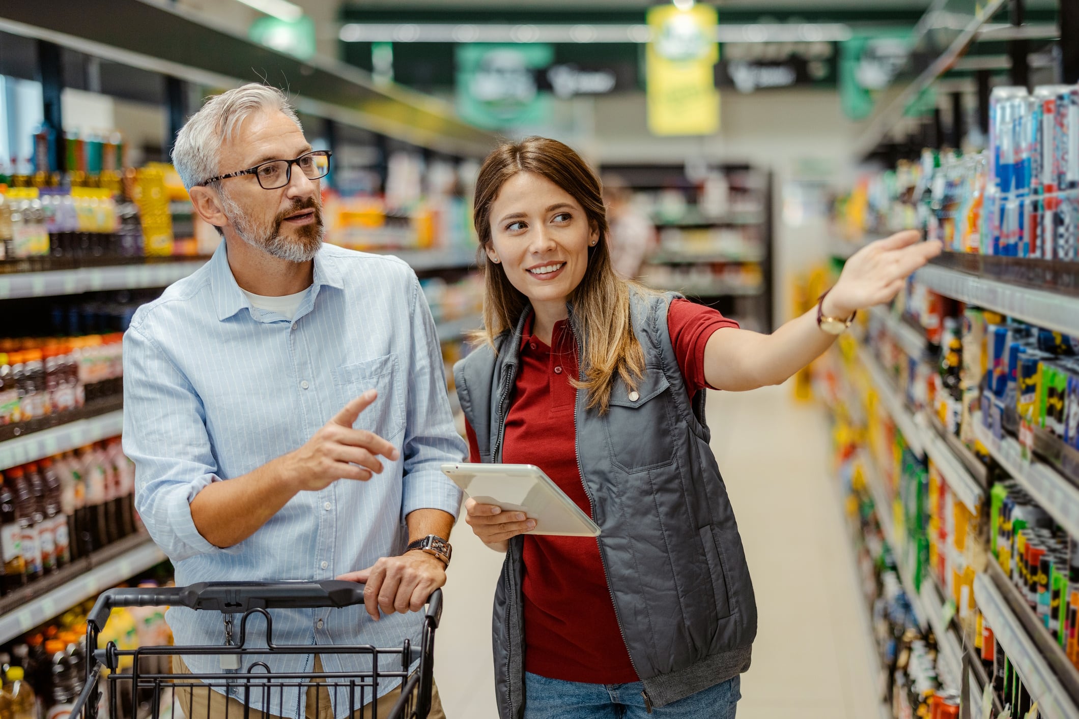 Saleswoman assisting male shopper in Supermarke
