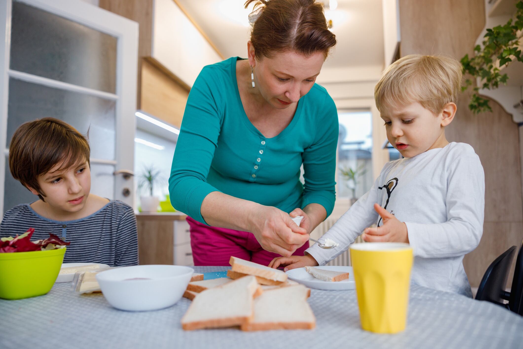 Mother standing by the table and making sandwiches for her sons zoranm