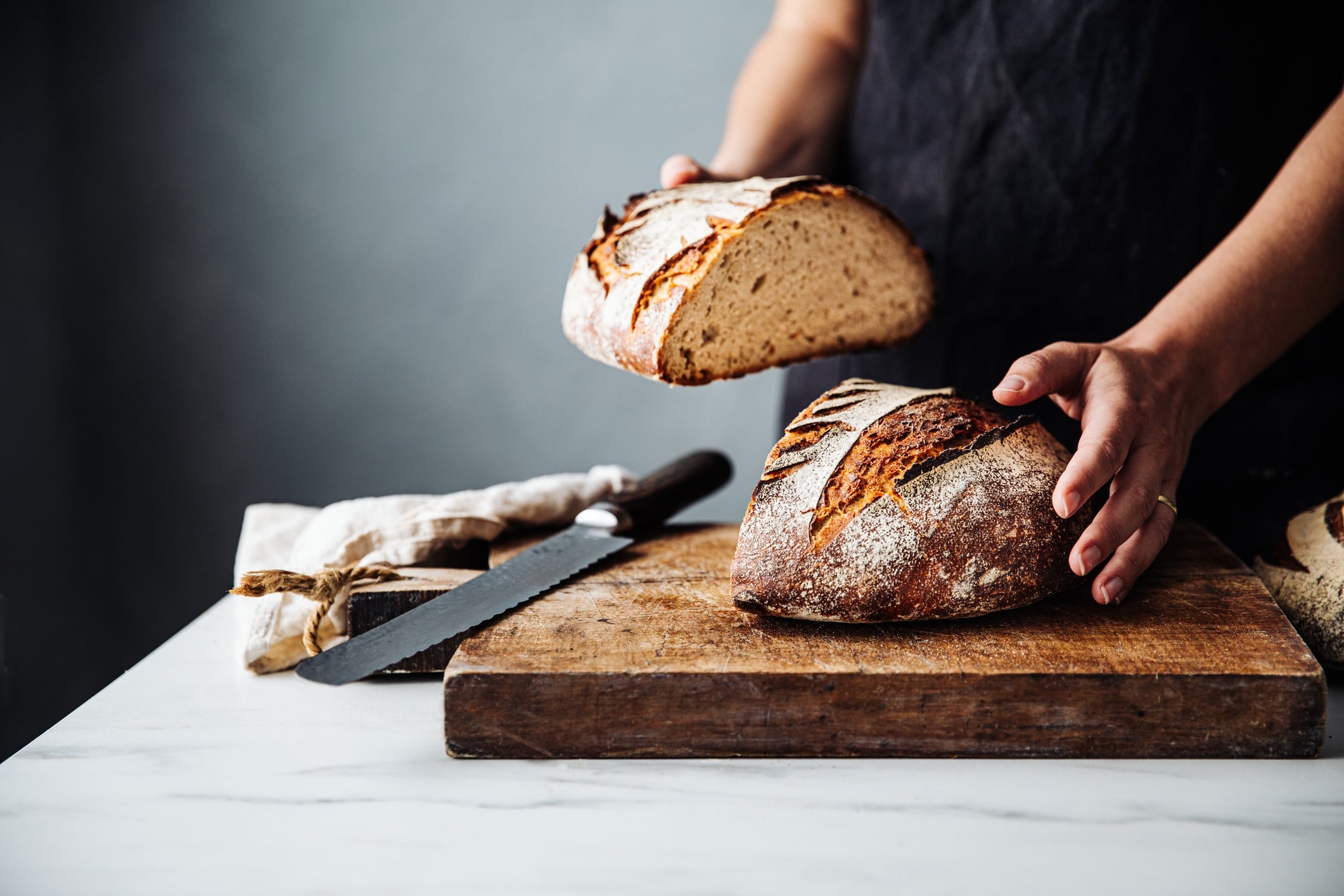 Woman holding bread on cutting board in kitchen