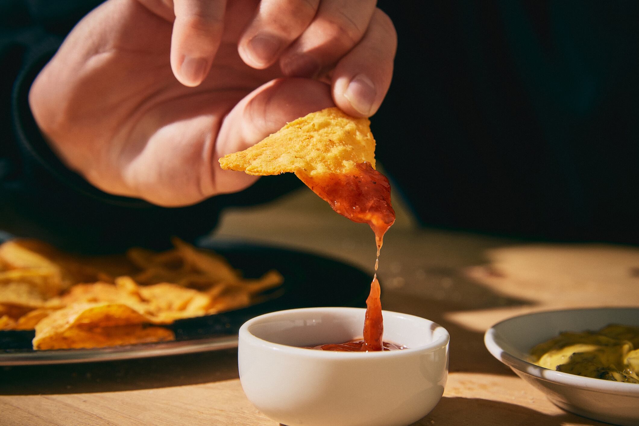 Closeup hand dipping chip into salsa master1305 GettyImages