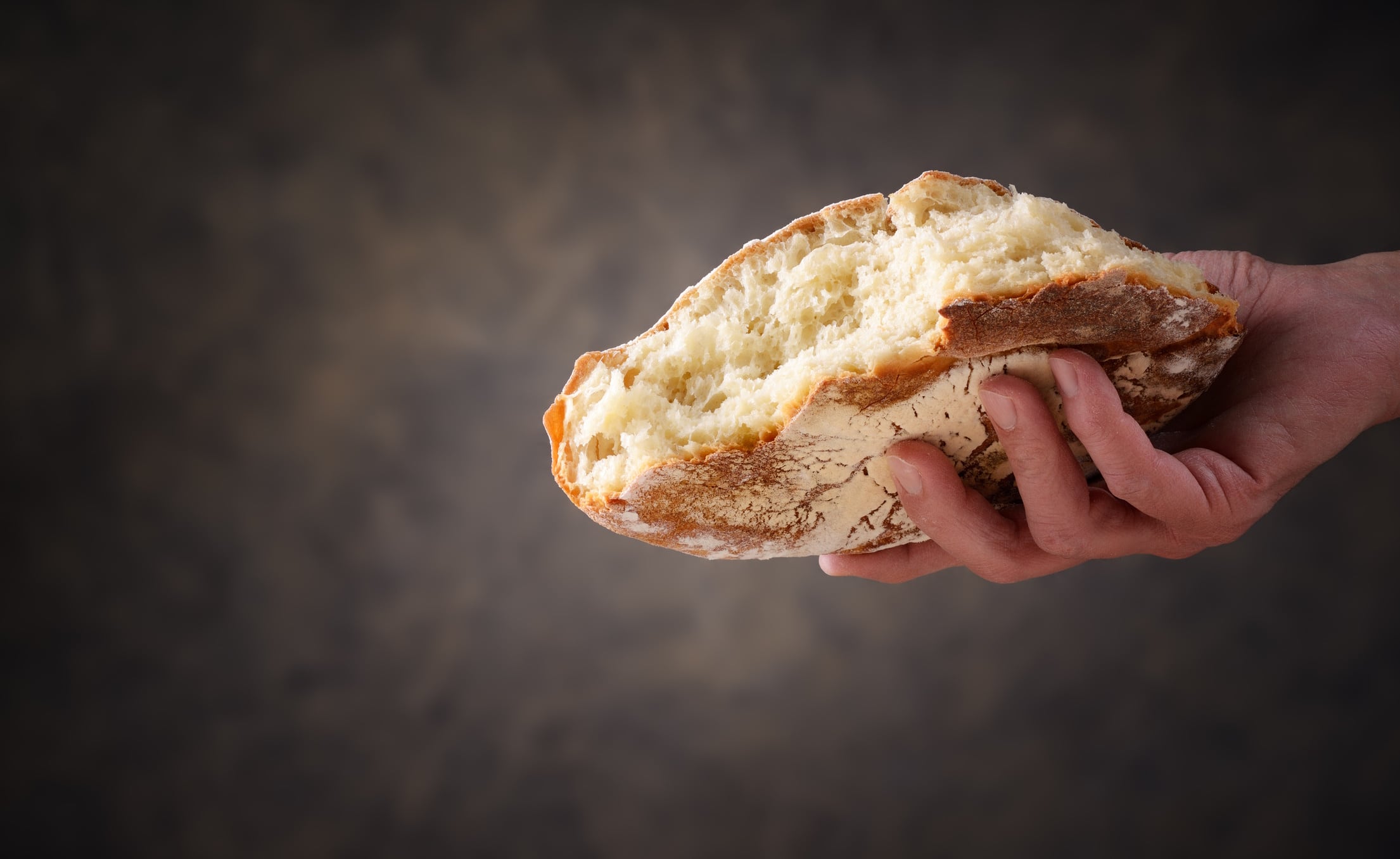 Hand holding piece of sourdough bread