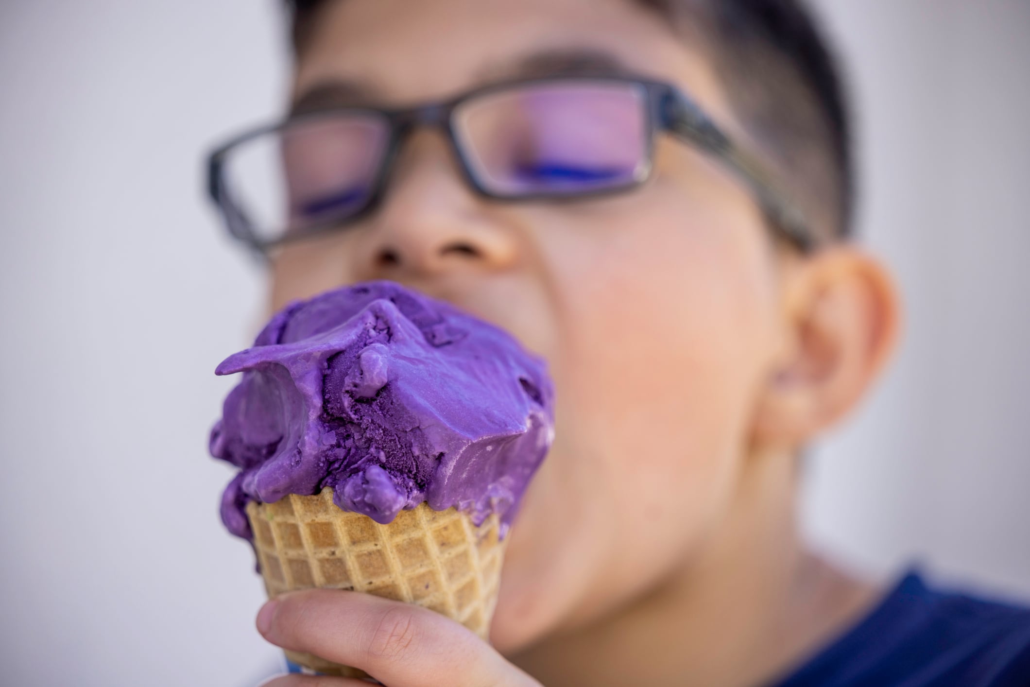 High quality stock photo of a Asian American mixed race boy eating ube ice cream on a hot day.