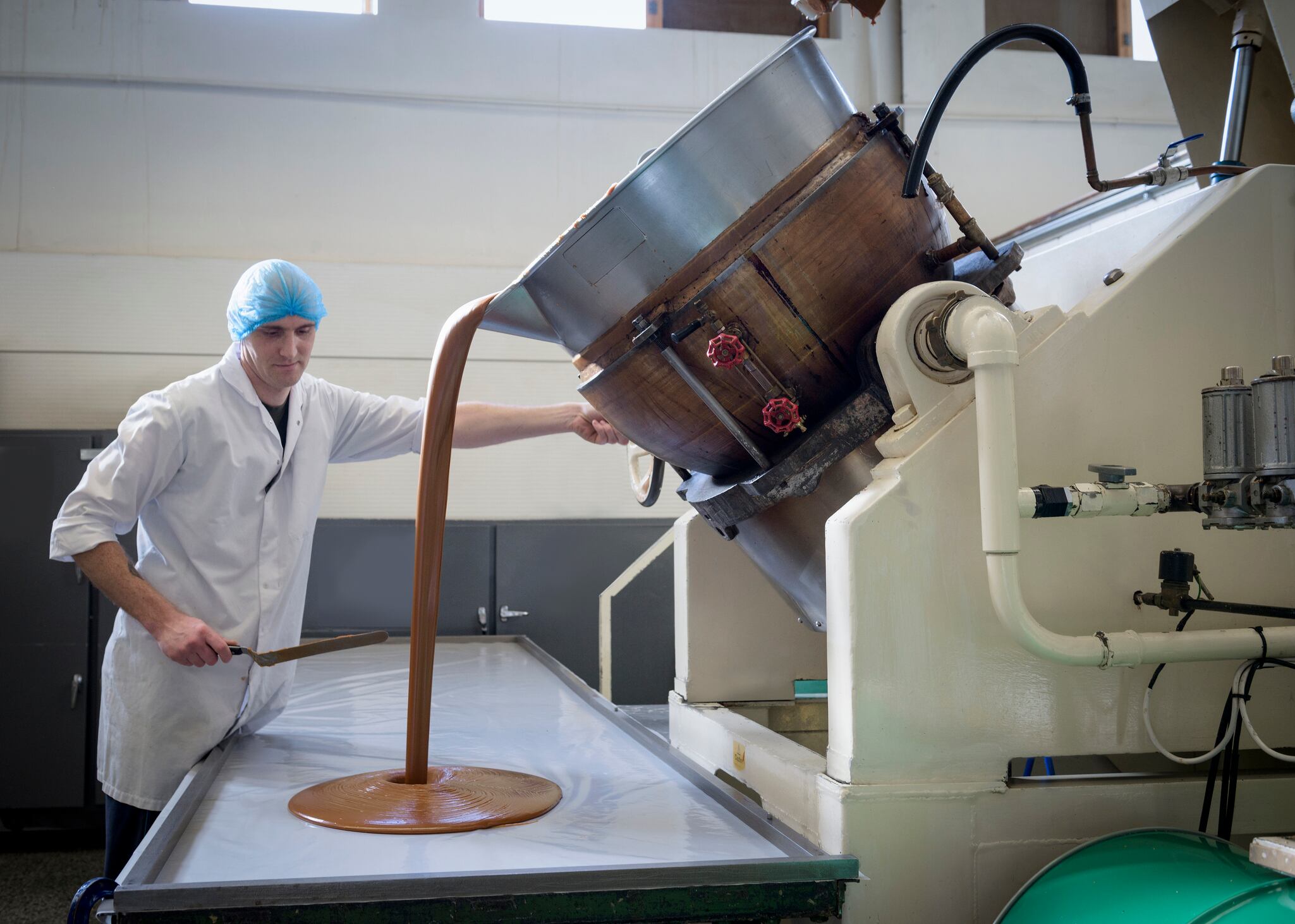 Worker pouring confectionery fudge in chocolate factory.