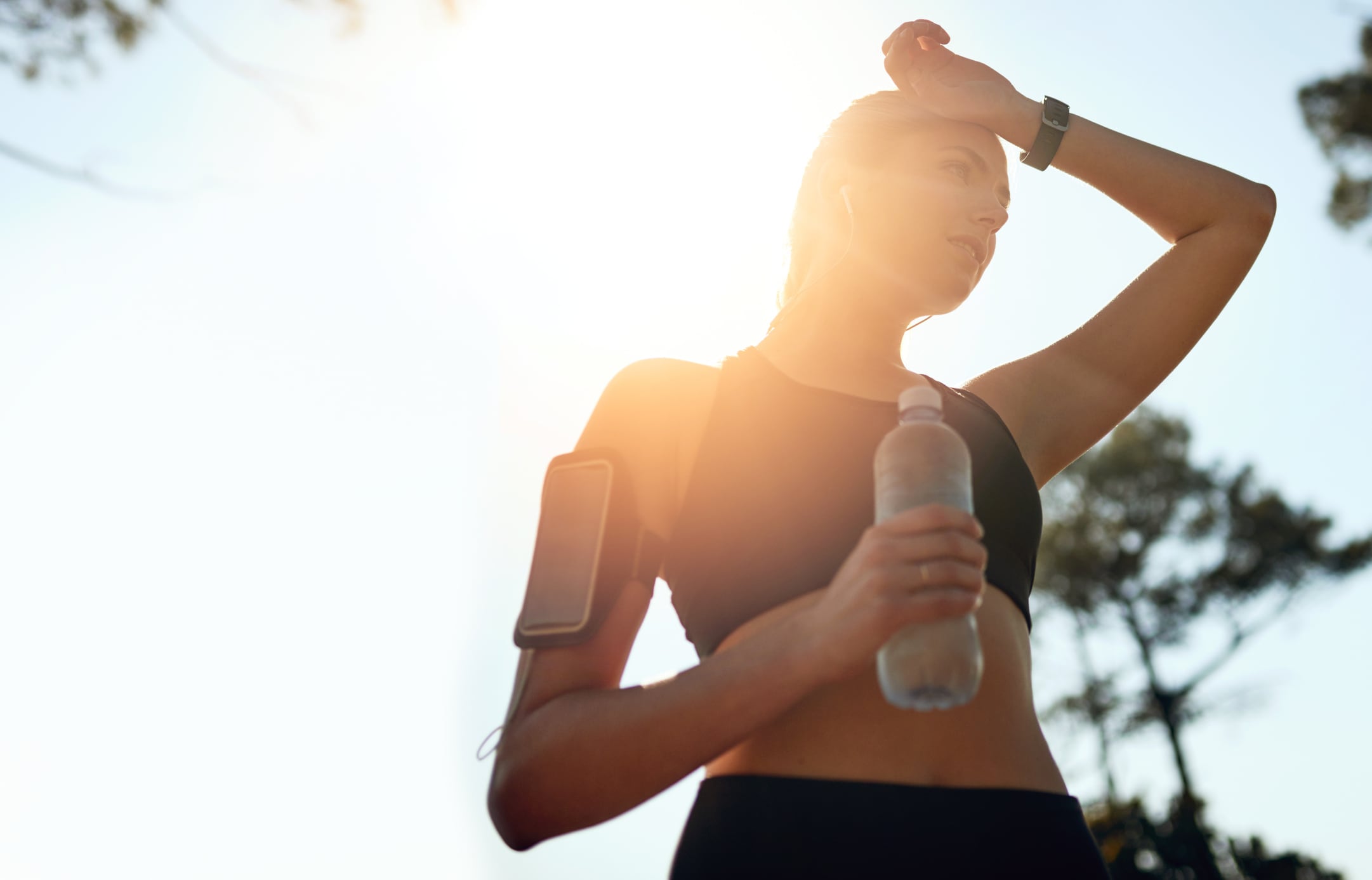 Shot of a fit young woman stopping for a drink of water during a run outdoors