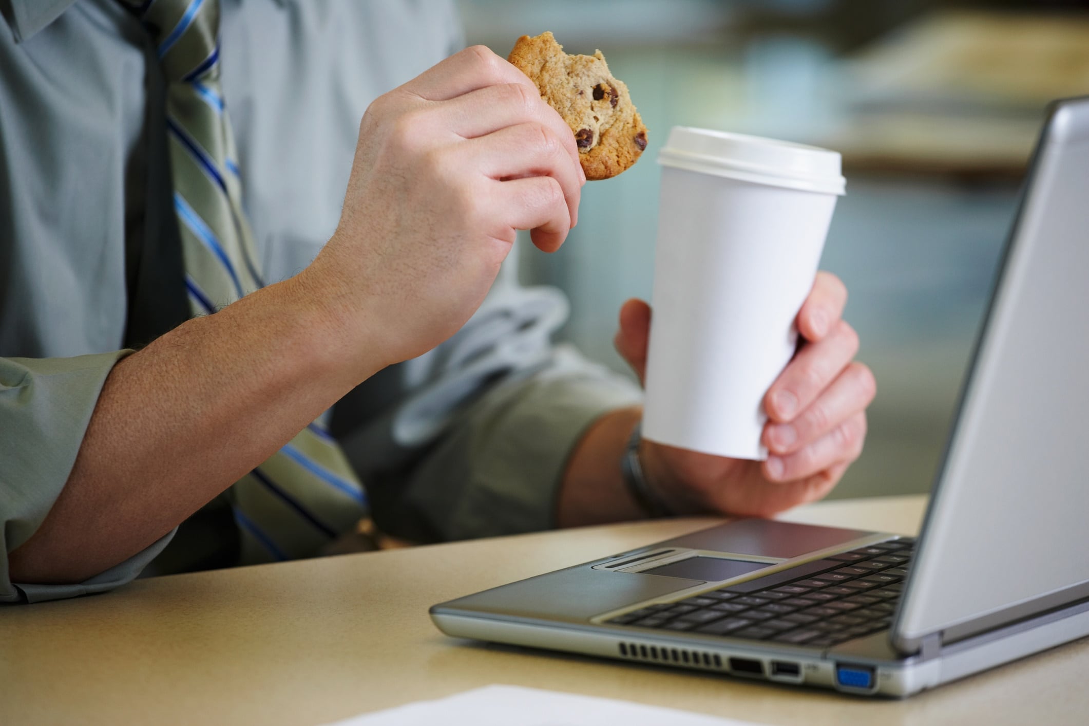 Man at his desk with a coffee and cookie