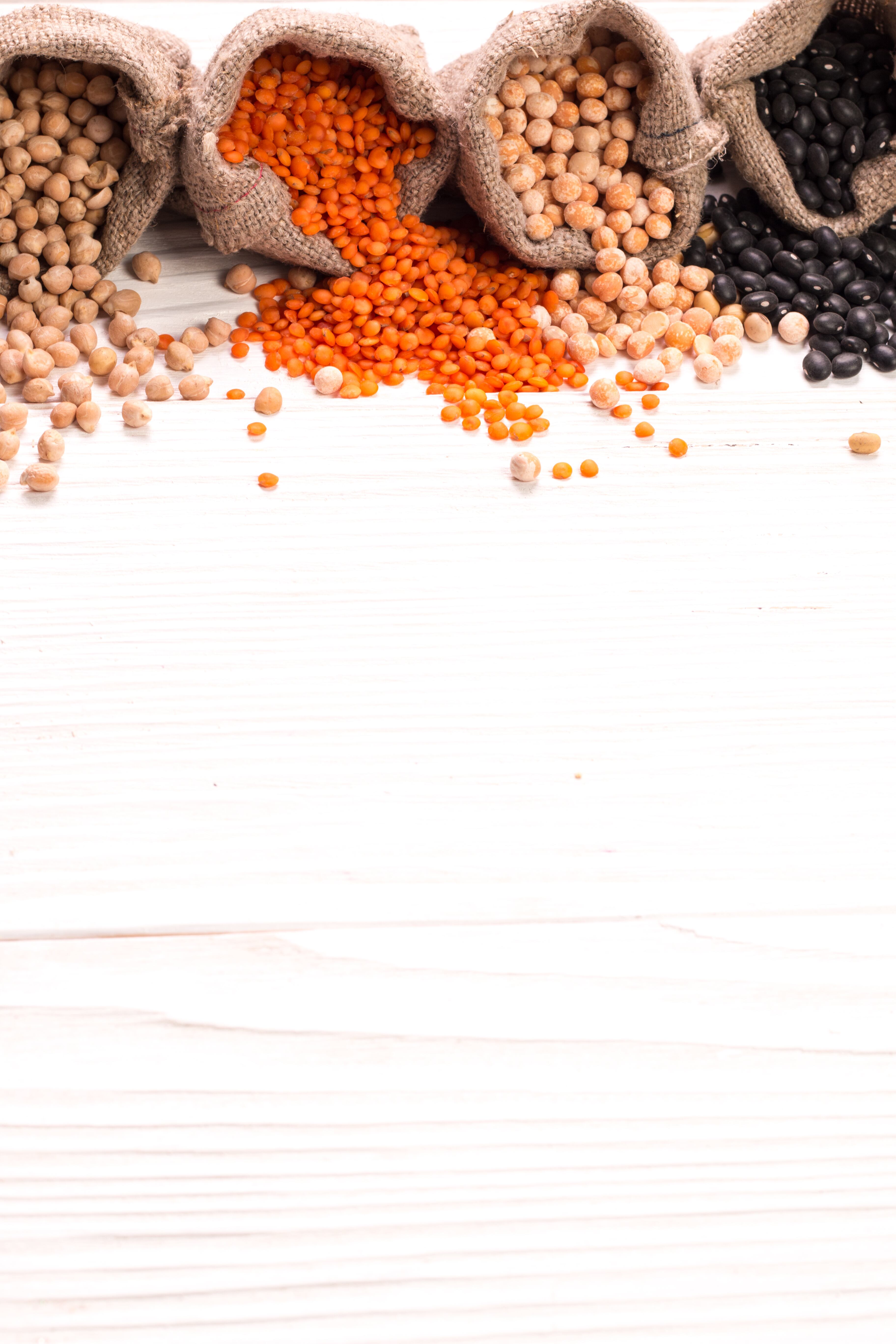 Bowls of various legumes on wooden background