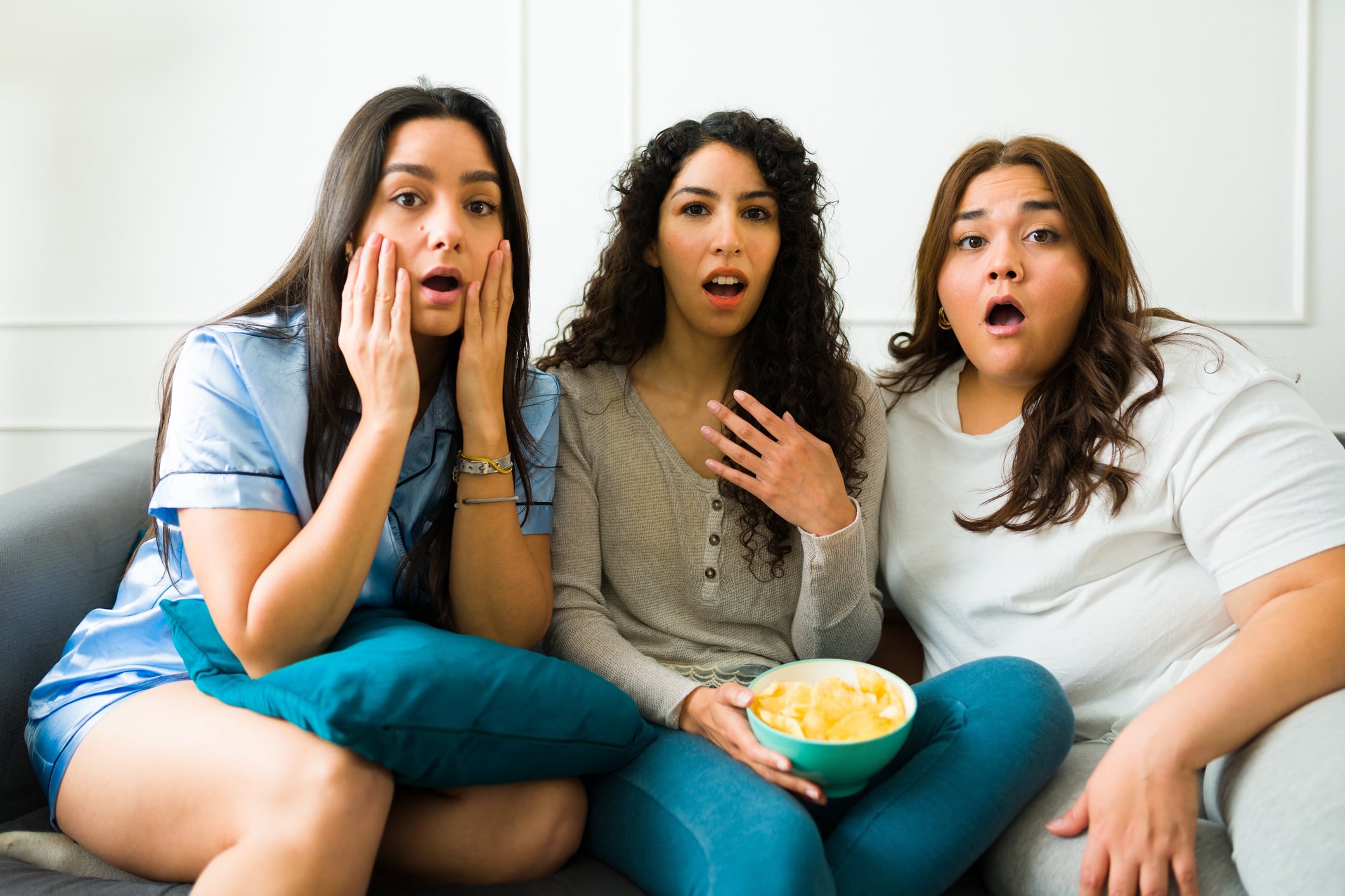 Group of surprised friends eating potato chips