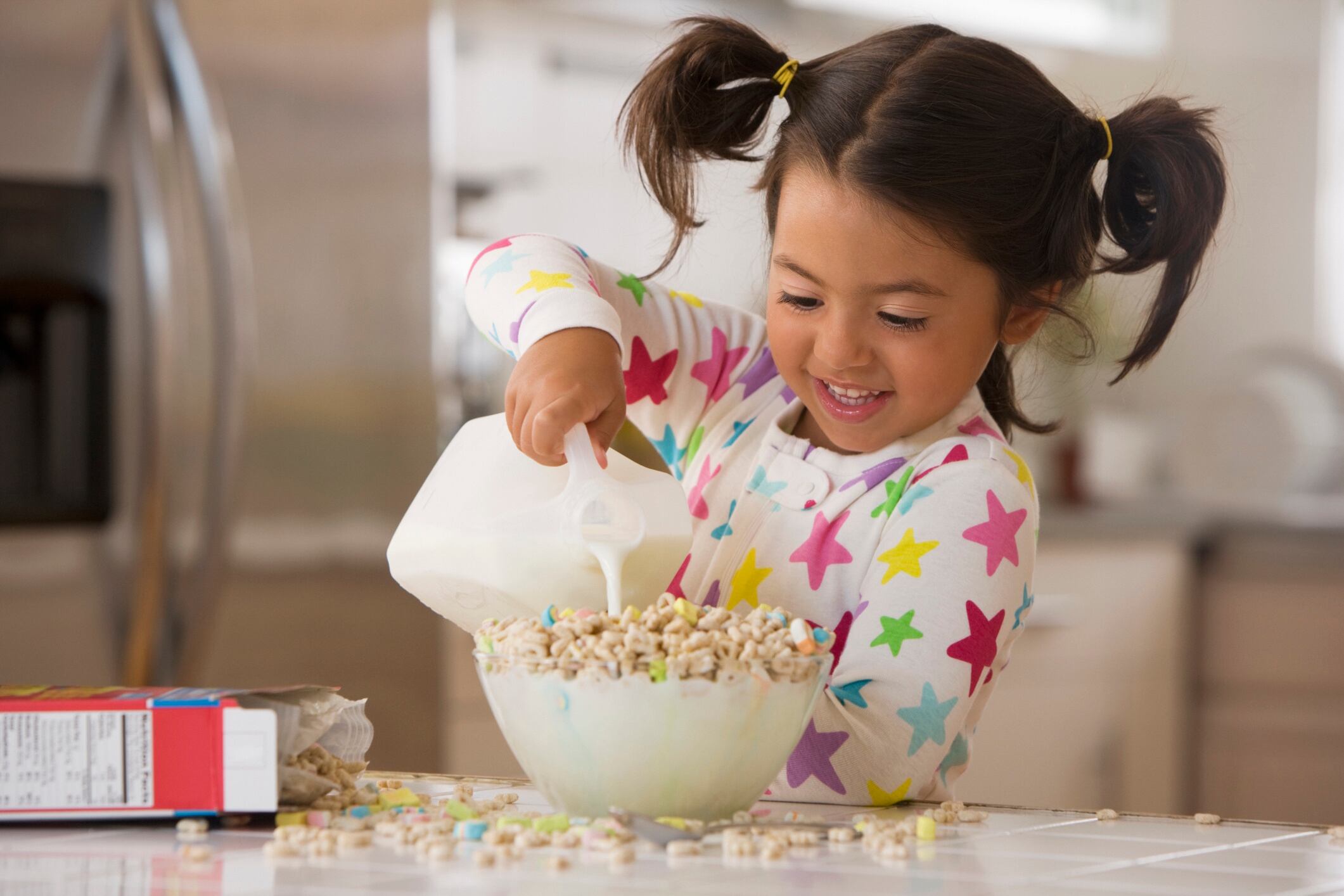 Young girl pouring milk into breakfast cereal Jose Luis Pelaez Inc GettyImages