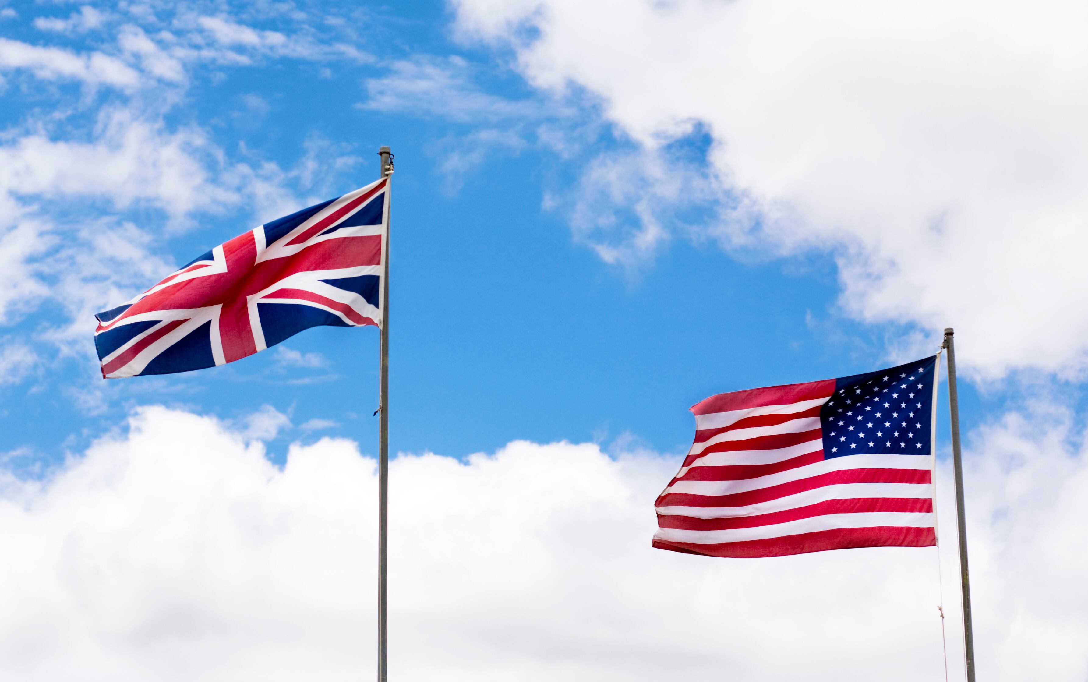 UK and US flag against sky backdrop