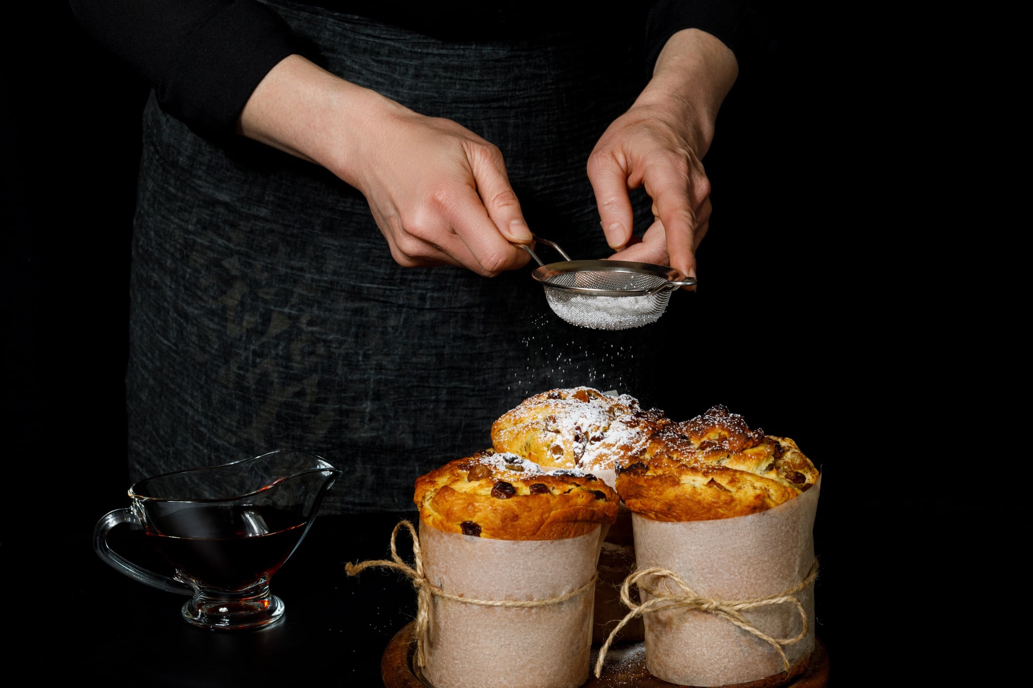 A baker sprinkles icing sugar on craffins