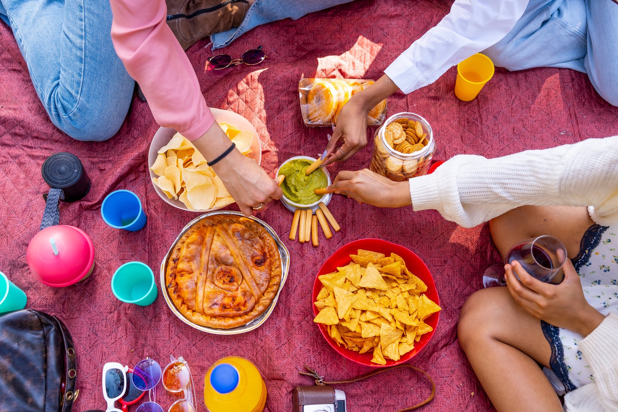 Friends enjoying a picnic with various snacks and drinks Unaihuiziphotography GettyImages