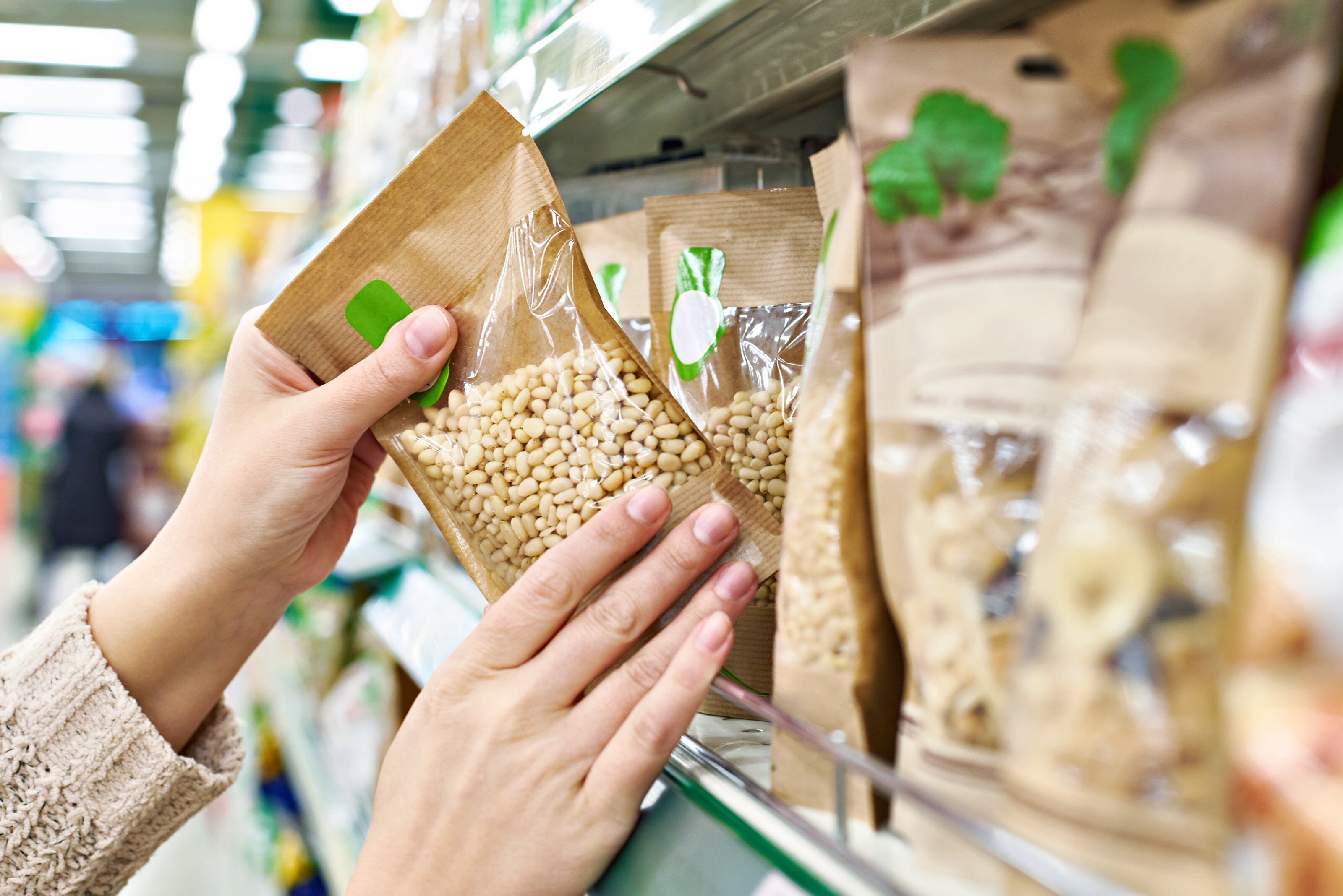 The BFY snacks market has emerged as one of the fastest-growing sectors in food: hands reaching for pine nuts on a grocery shelf