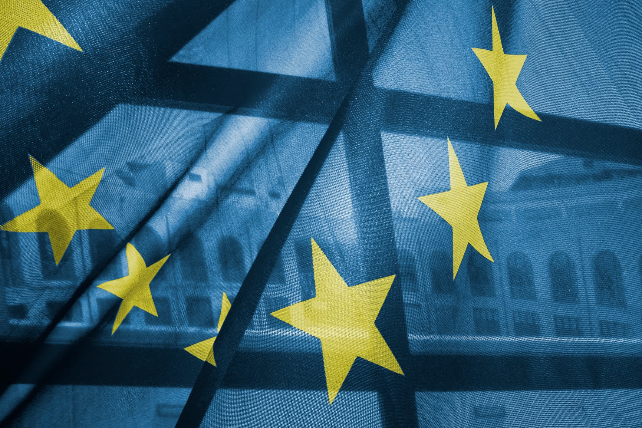 Classical building appears through a EU flag.