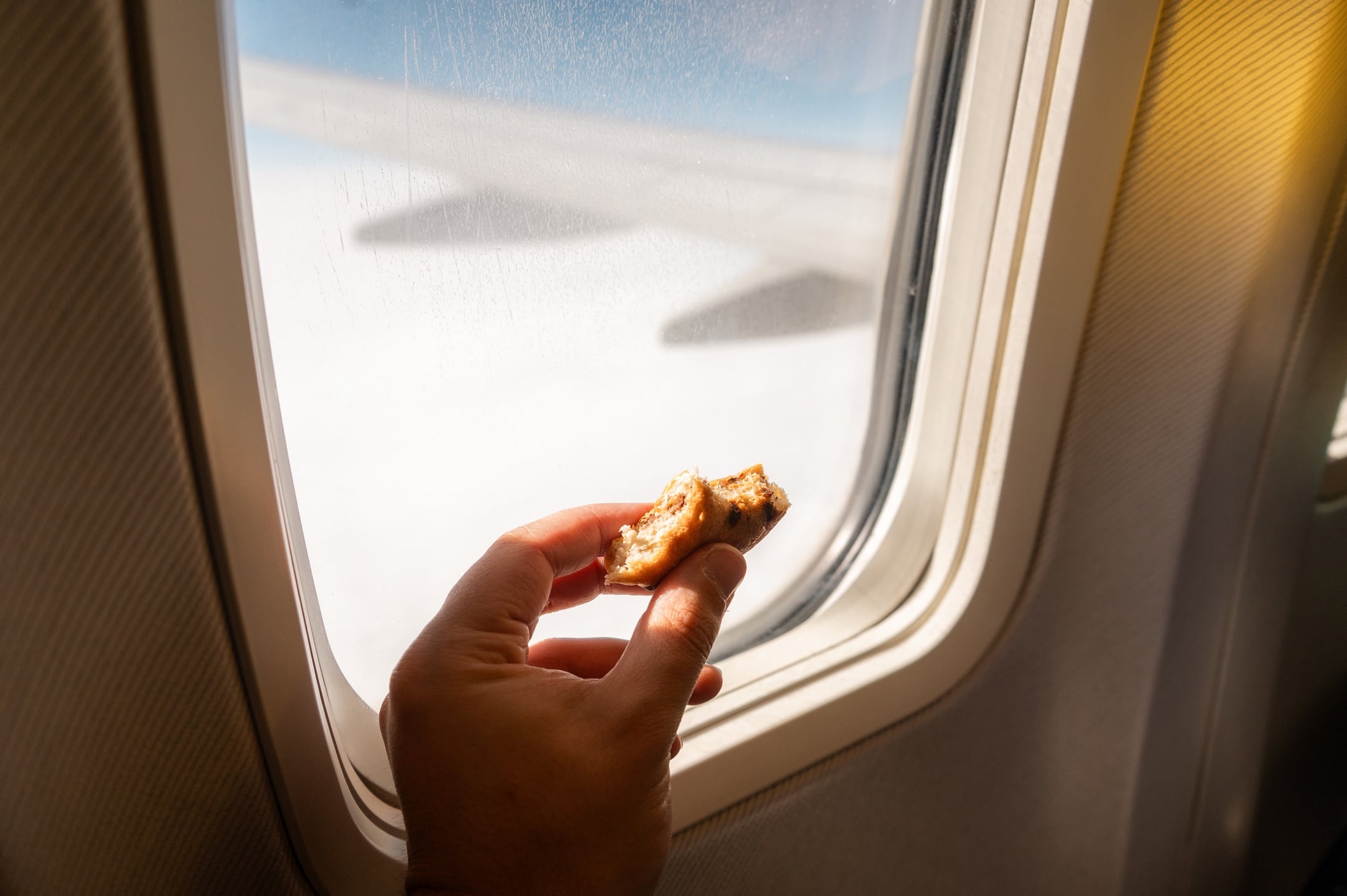 A hand holding a bun inside an airplane MarioGuti GettyImages