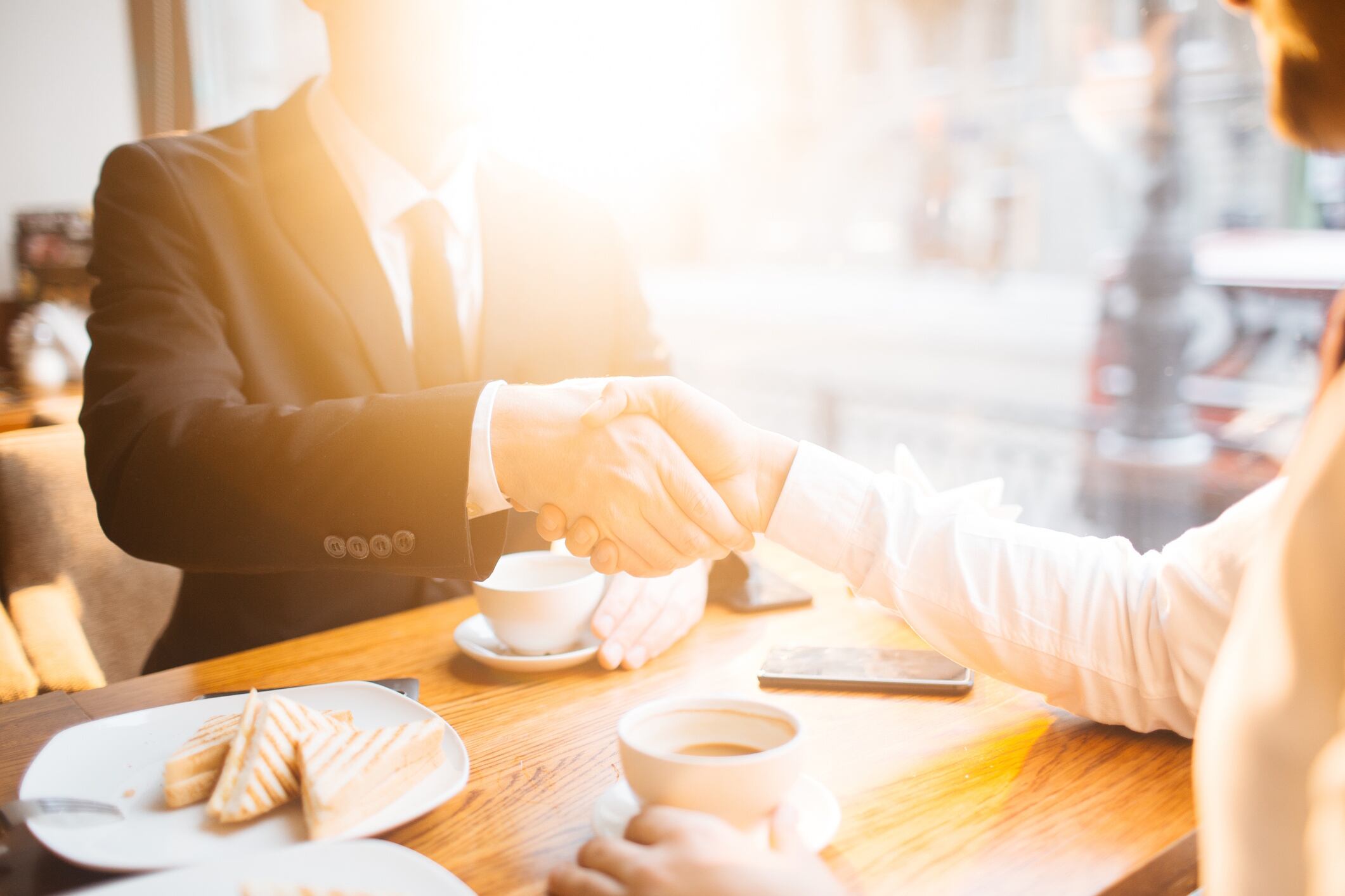 Businessmen handshaking in cafe during lunch