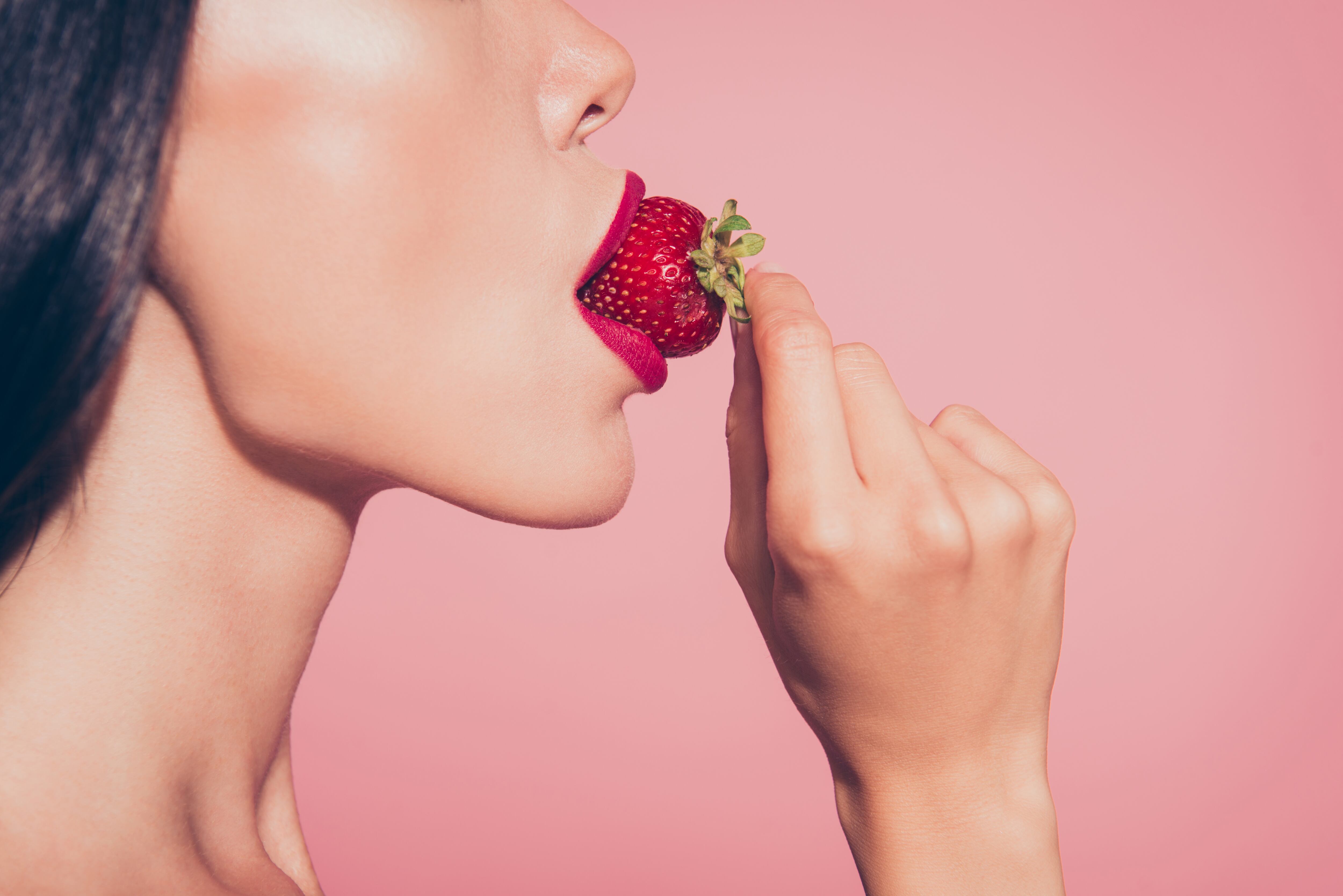 Close up of woman eating a strawberry
