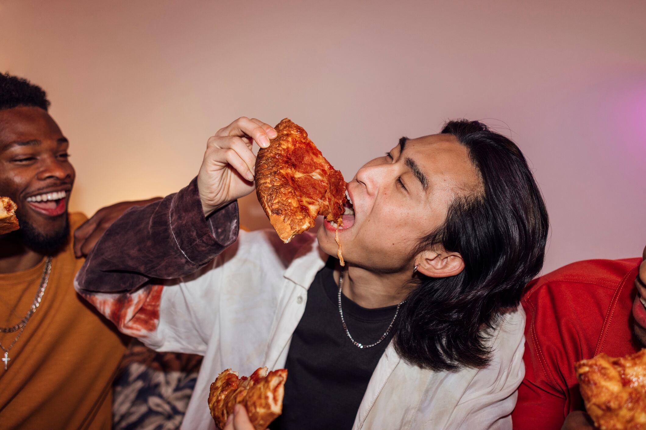 A group of young men enjoying a party at a house in North Shields, North East England. They are all socialising together, eating pizza. SolStock GettyImage