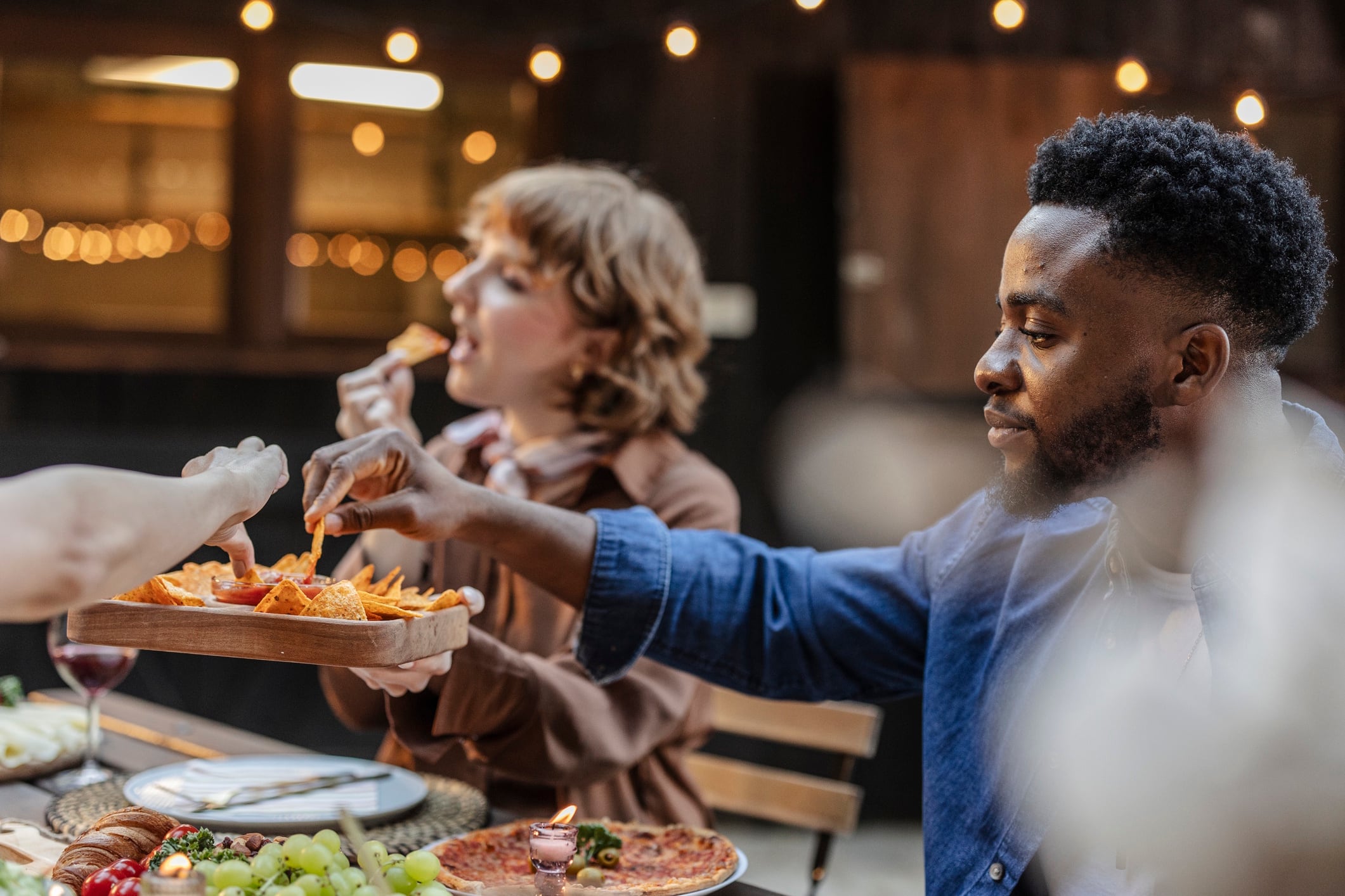Friends eating nachos and pizza at a multiracial party outdoors Jose carlos Cerdeno GettyImages-2187089050.jpg