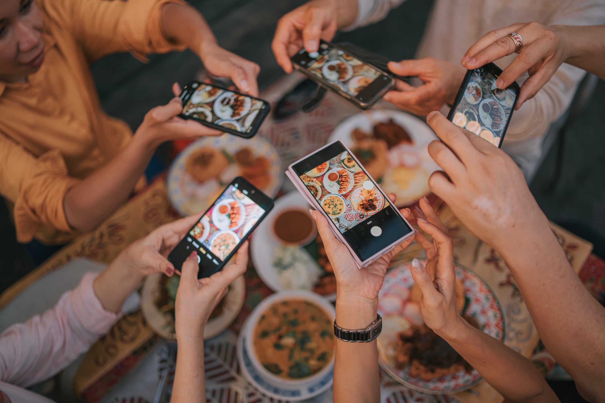 POV group of tourist taking photos of various food on table with smartphone in outdoor restaurant. mature travellers exploring local foods while travelling Edwin Tan GettyImages