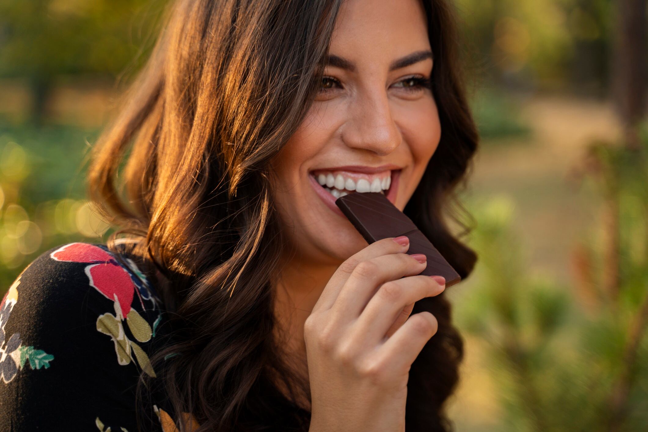 Closeup portrait of woman eating chocolate and smiling.