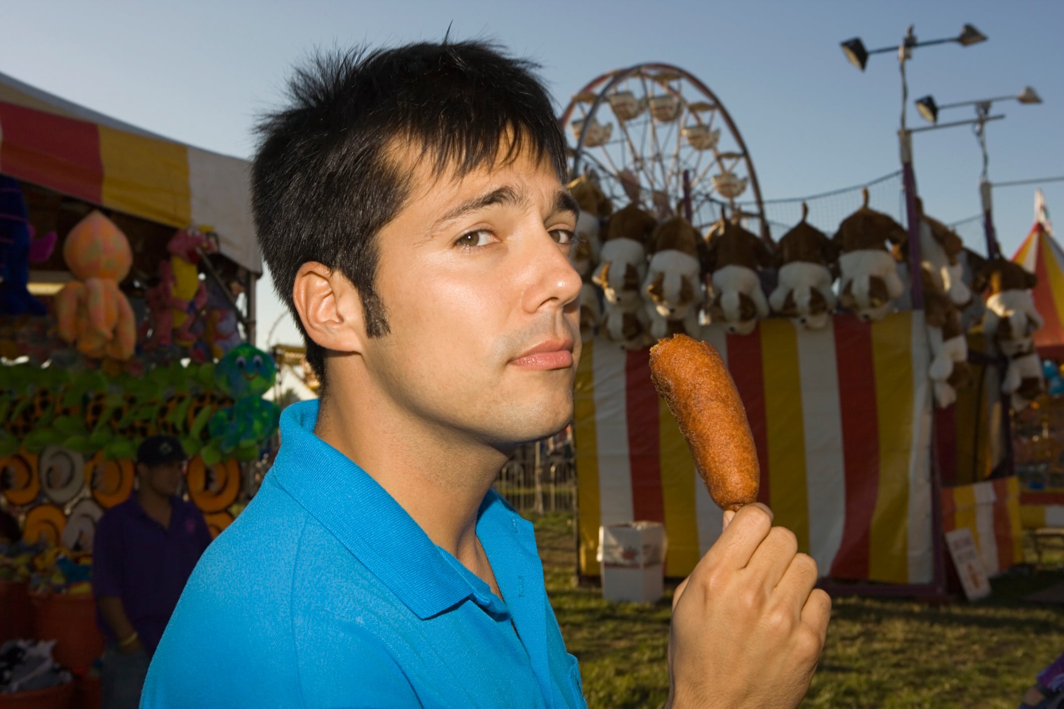 Man eating a corn dog at a carnival