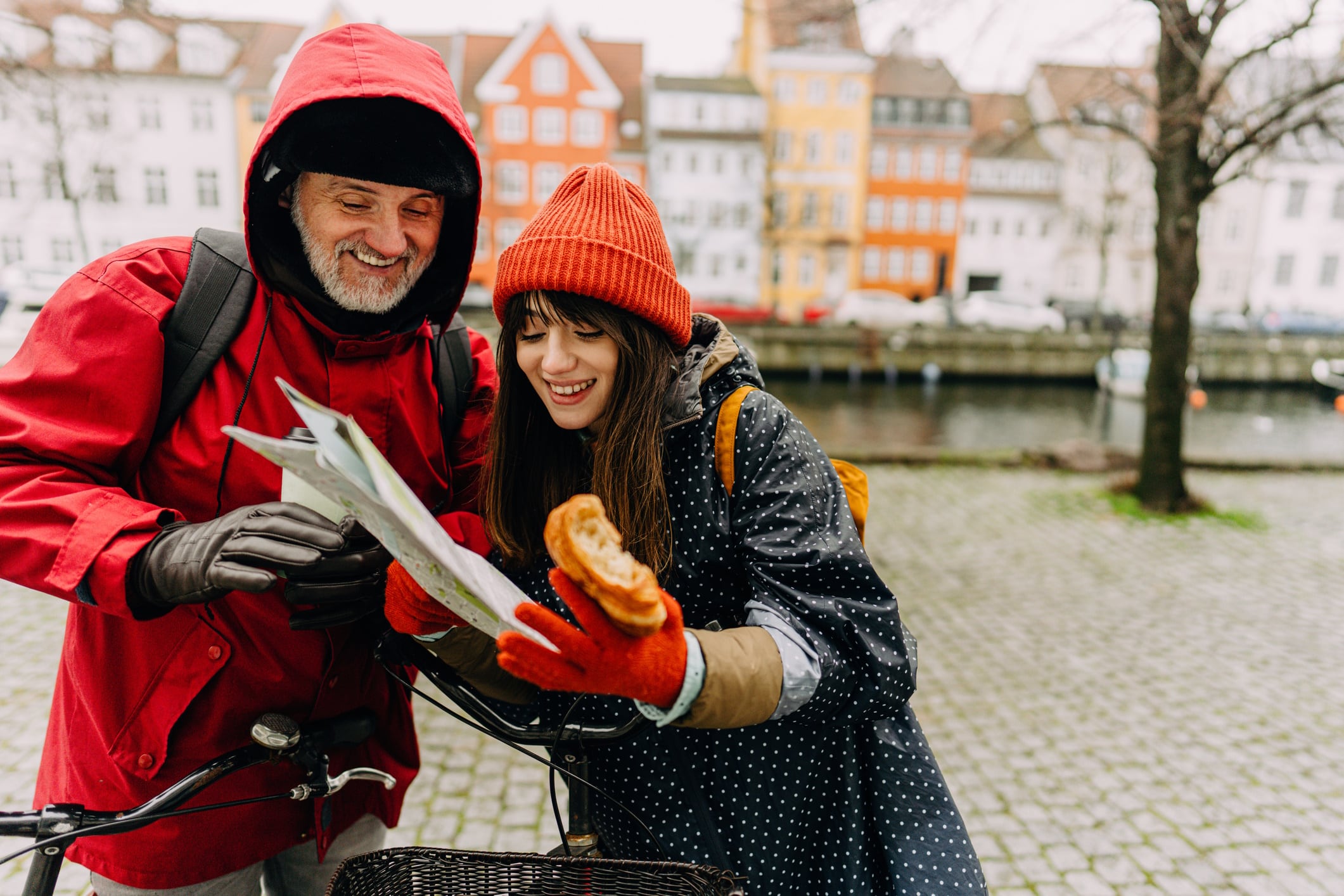 Young woman and her father looking at a map while exploring Copenhagen by bike