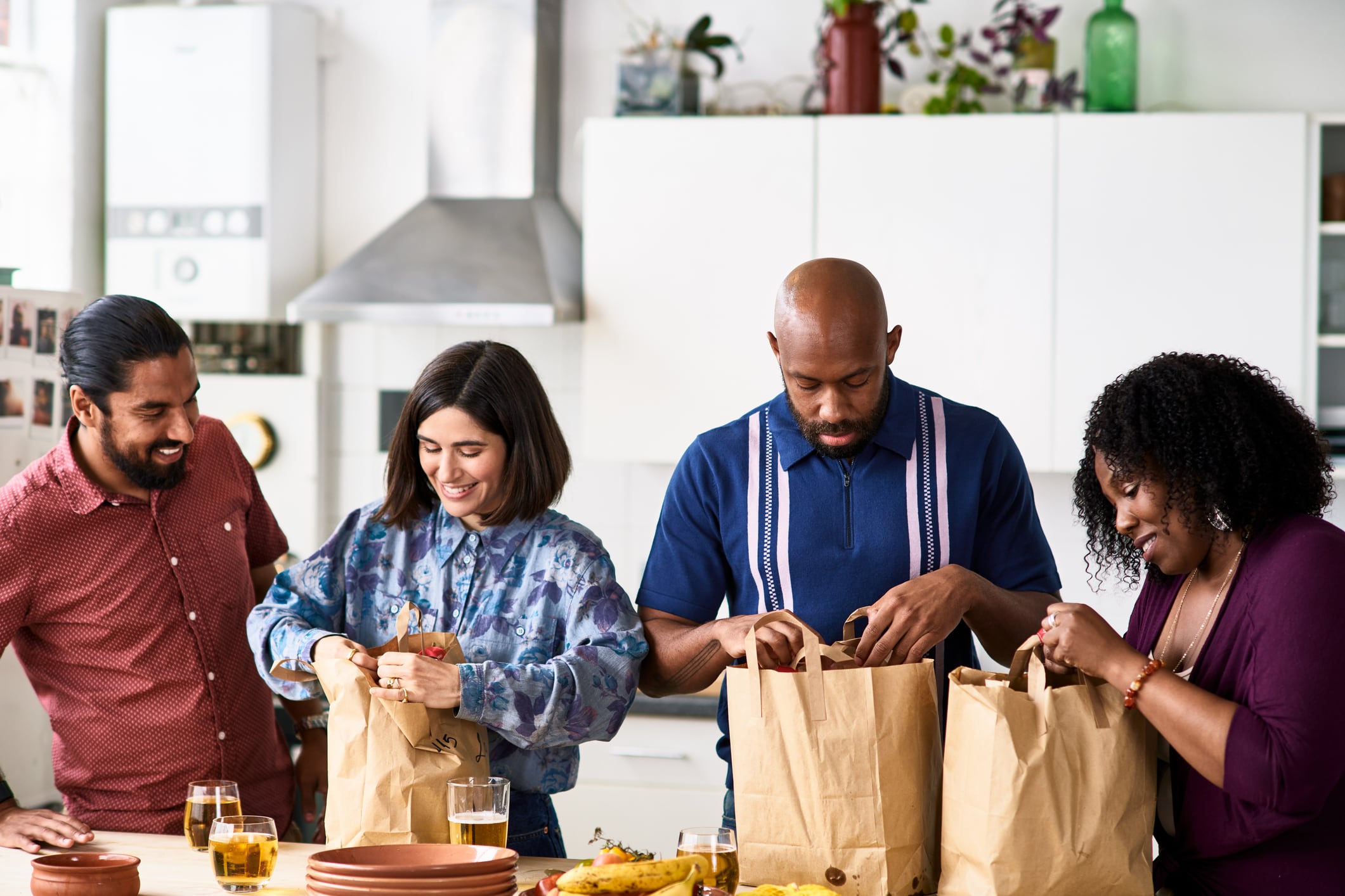 Image: Two women and two men having night in at home with takeaway meal, opening bags and looking inside