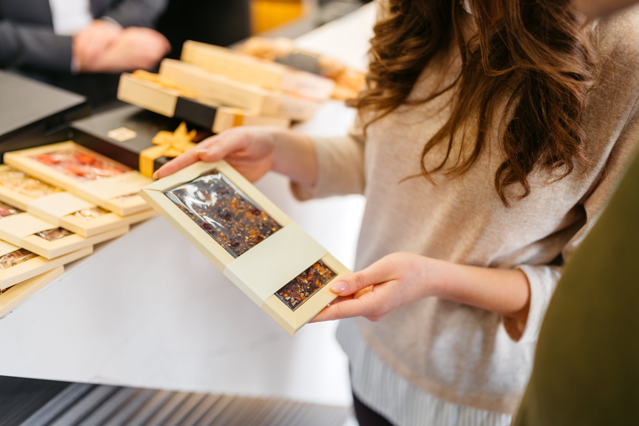 Young couple looking at chocolate bar products in a liquor and chocolate store. Close-up.