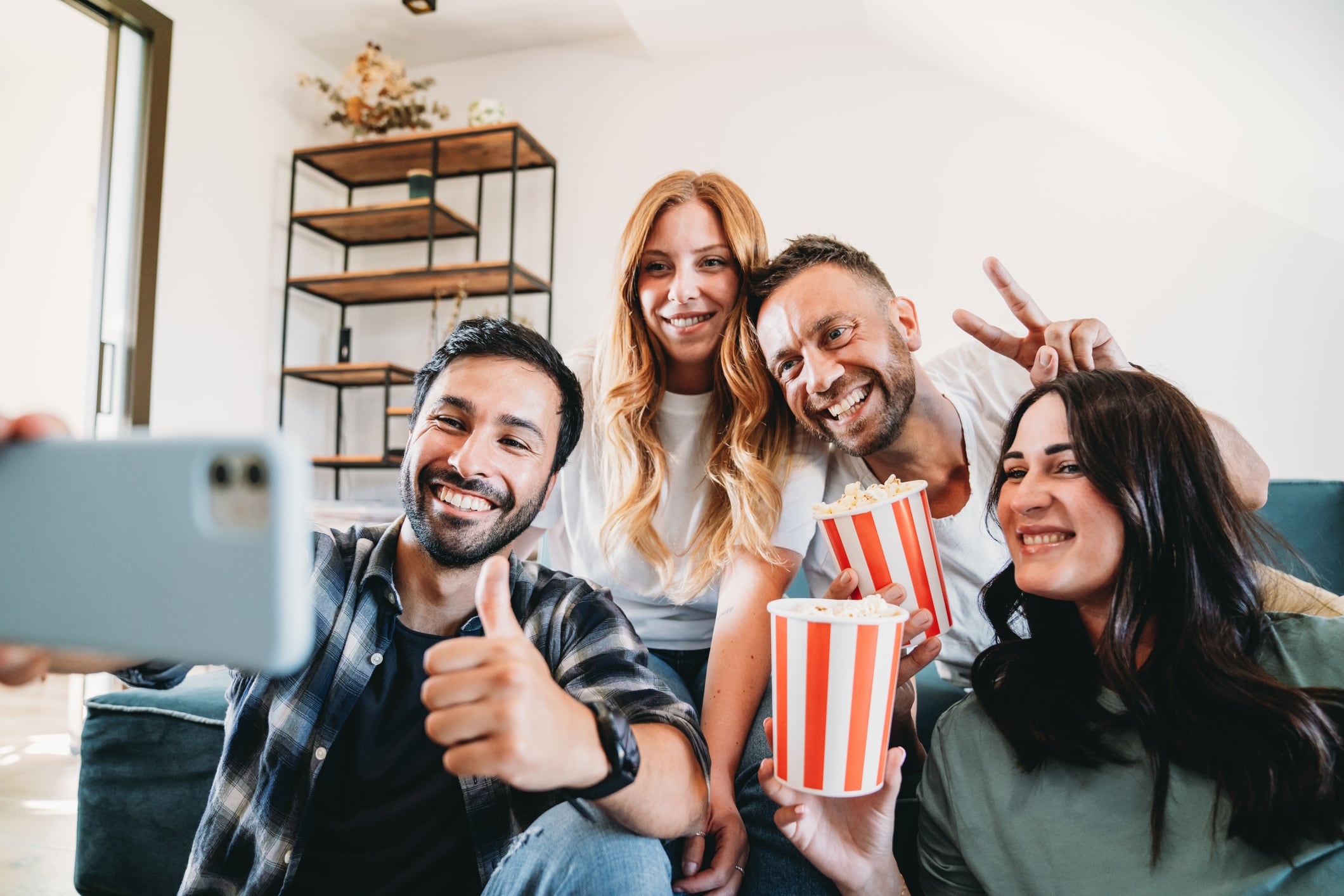 A group of four friends are taking a selfie during a movie afternoon at home