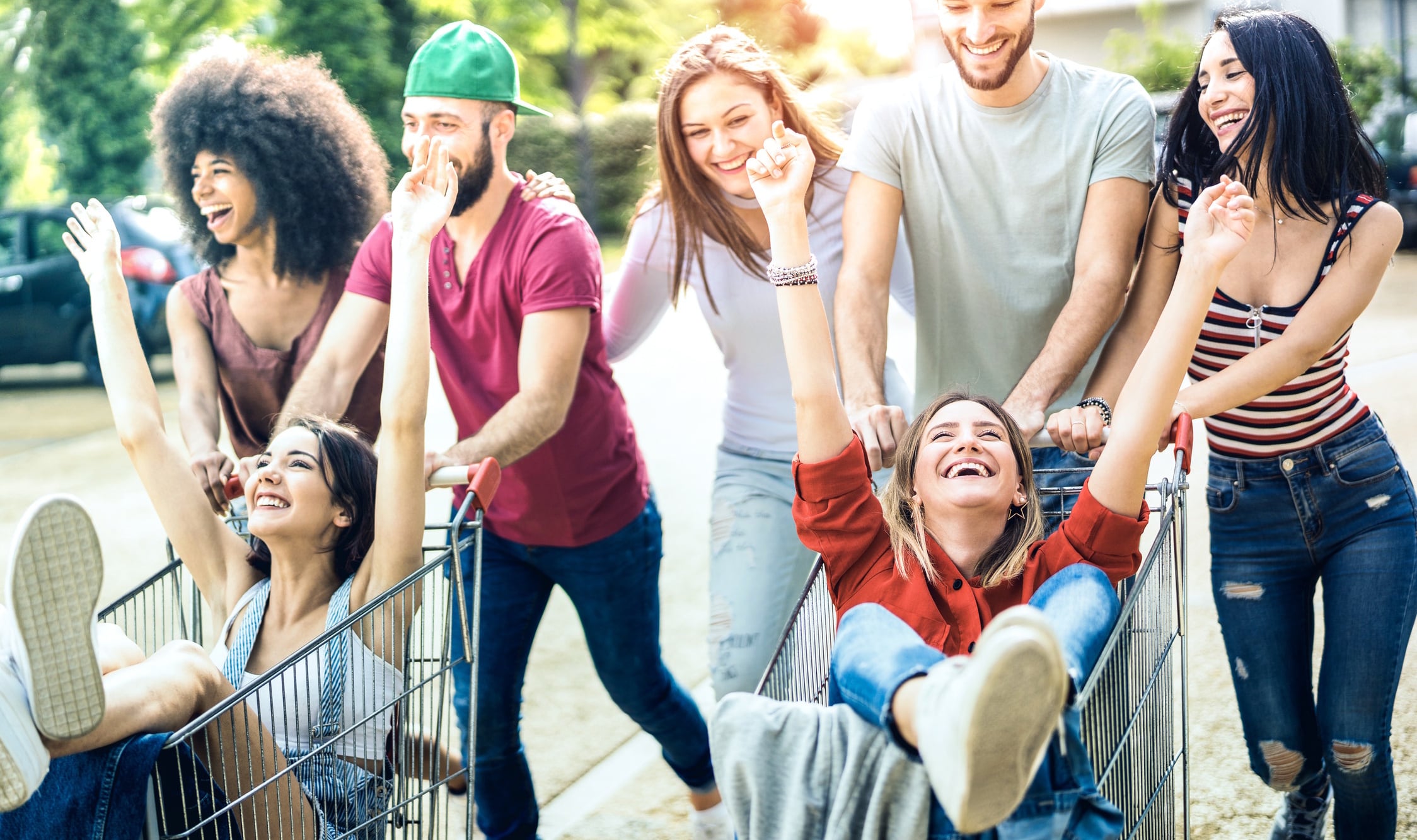 Young multiracial people having fun together with shopping cart - Millenial friends sharing time with trolleys at commercial mall parking ViewApart GettyImages