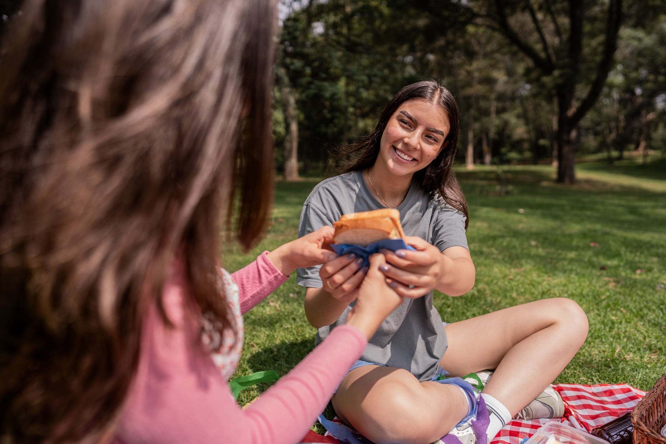 Two young girls eating a sandwich in the park