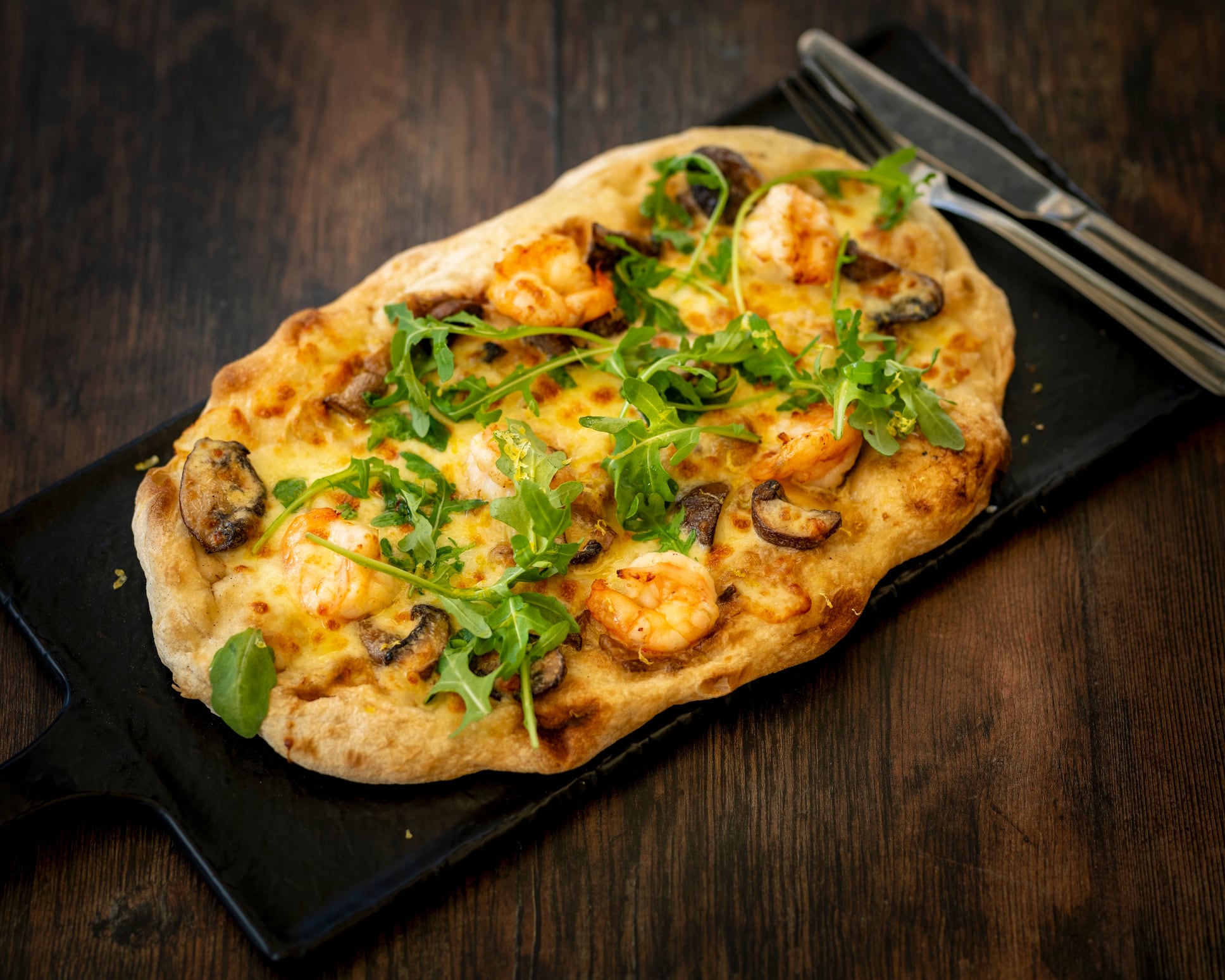 Villafranca Pinsa with porcini mushroom cream, tomato puree and tiger prawns, topped with rocket, Gran Moravia cheese and lemon zest Monty Rakusen GettyImages