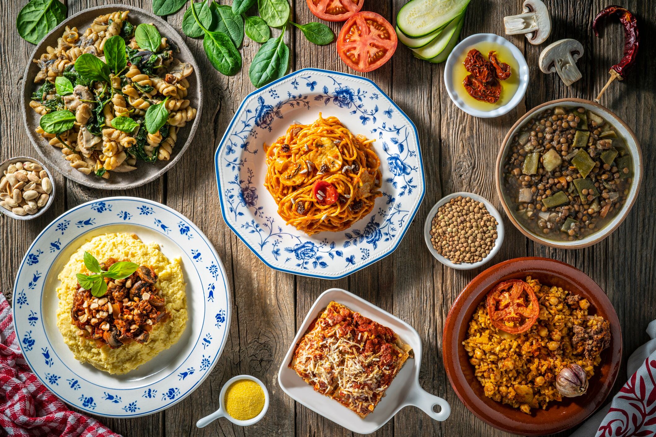 Vegan Mediterranean diet food arrangement, plant based recipes Mediterranean food as vegan Lasagna, Polenta, Spaghetti tomato sauce and Fusilli mushrooms, baked rice and lentils