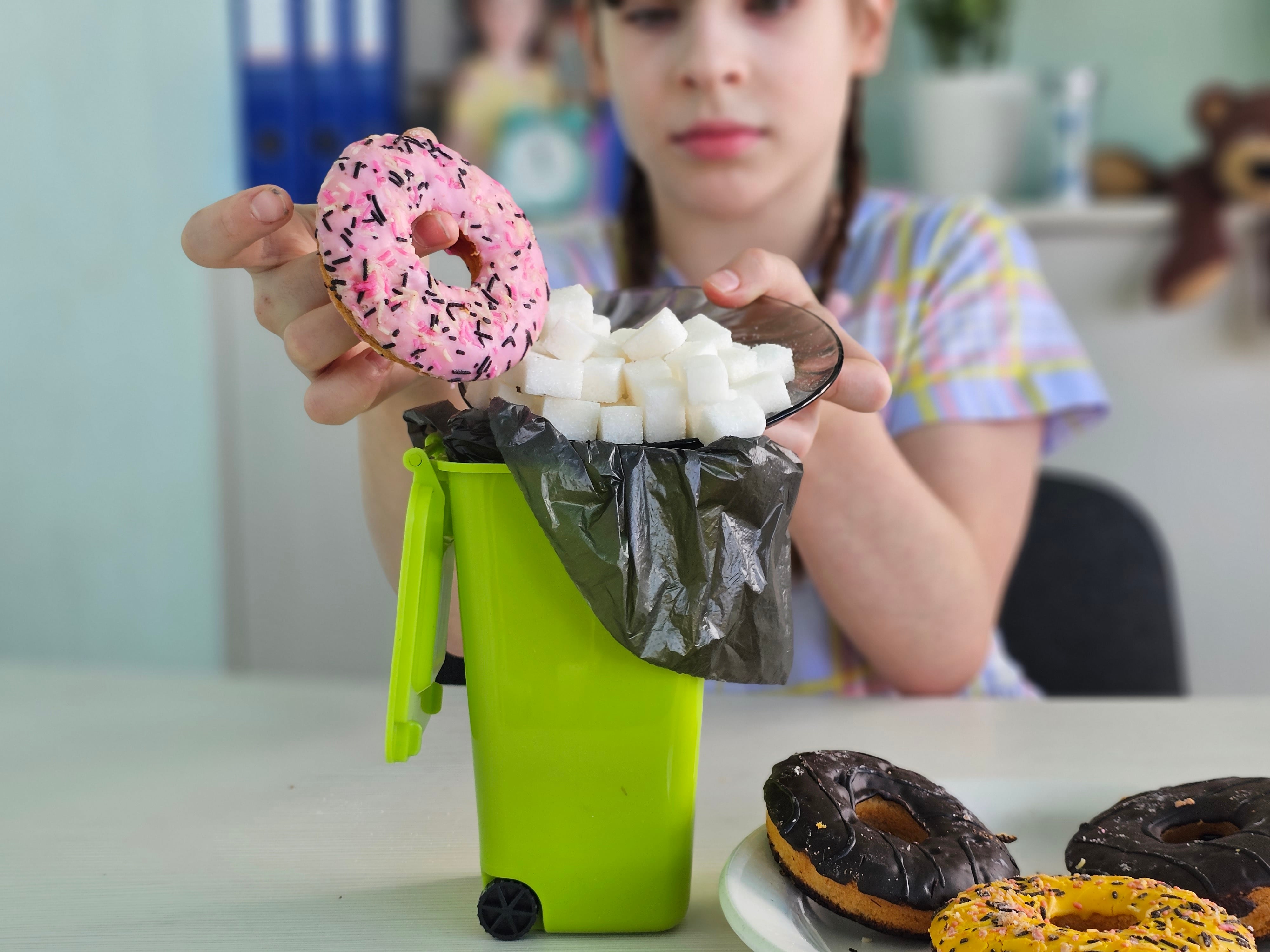 Child throwing high-sugar doughnut into the bin