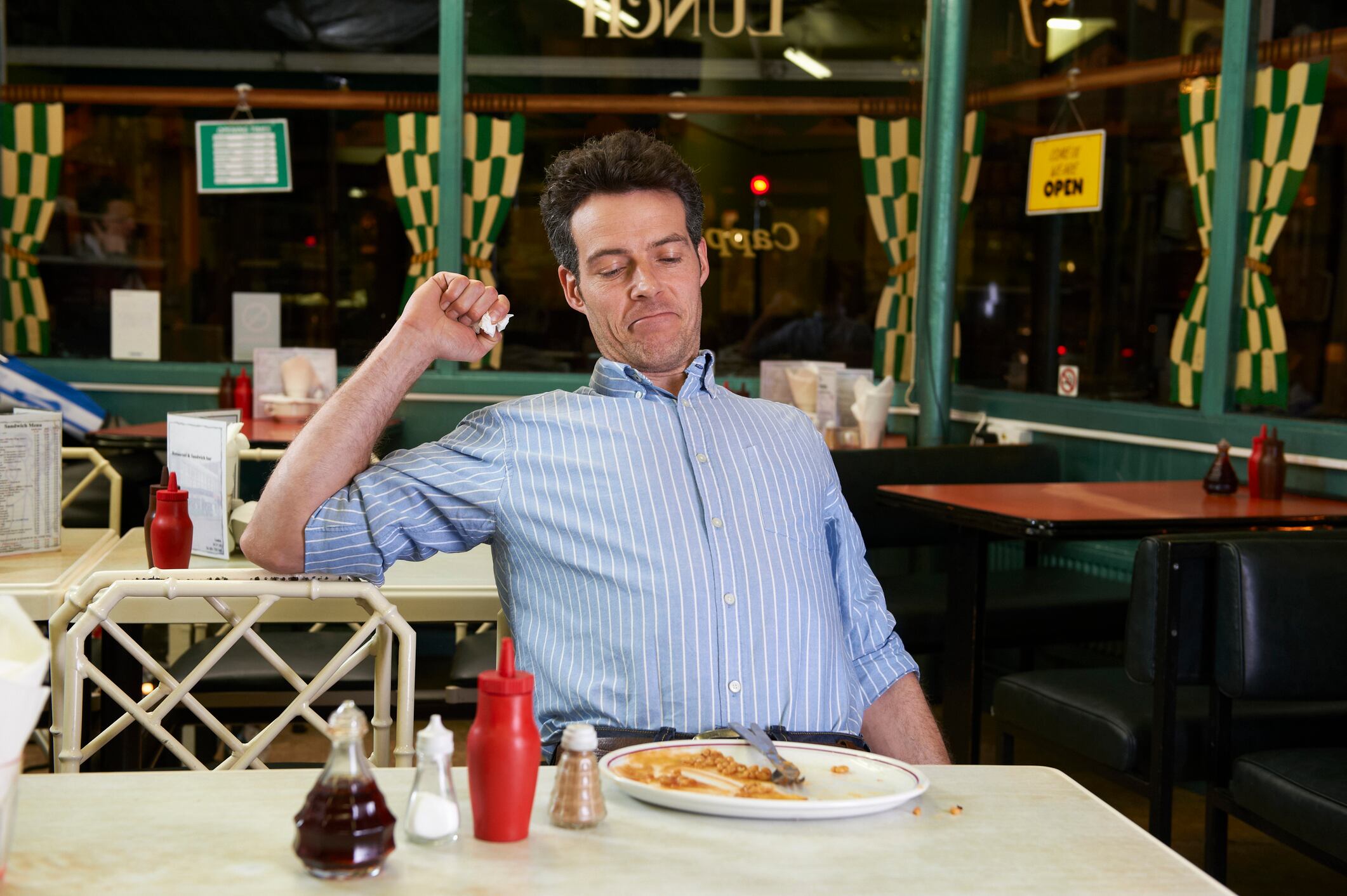 Man in cafe with empty plate, feeling full