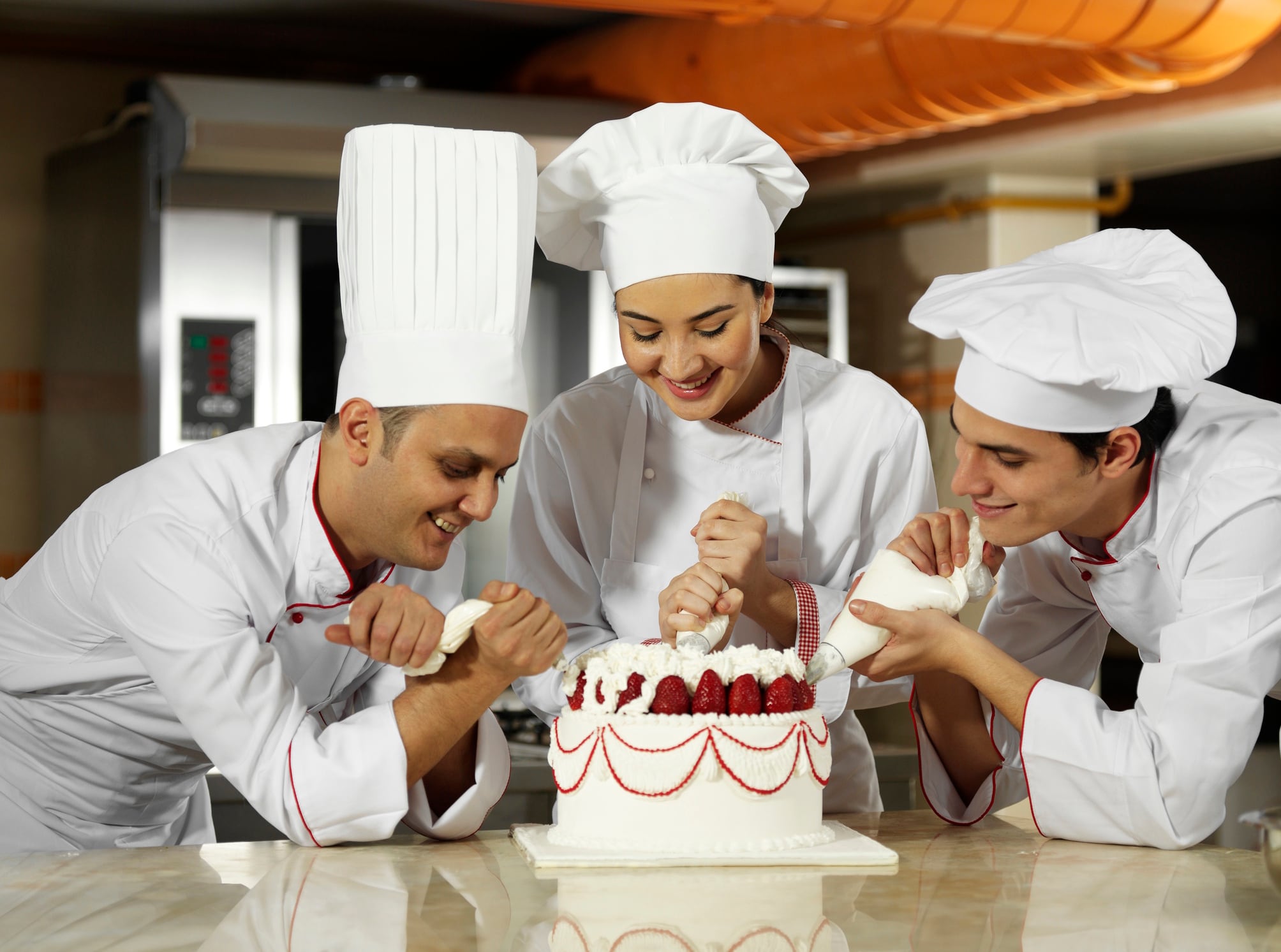 Group of pastry chefs decorate cake gerenme GettyImages