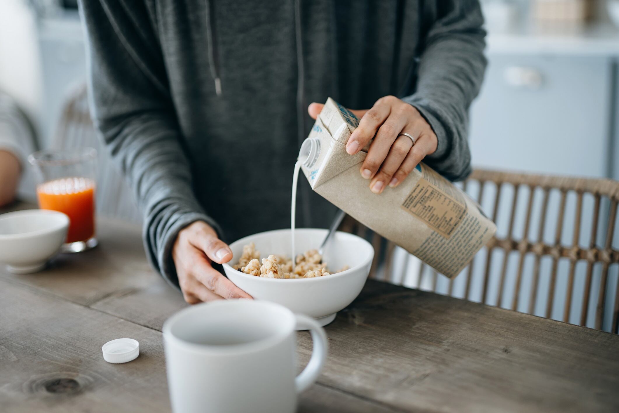 Cropped shot of woman preparing breakfast - pouring milk over cereal.