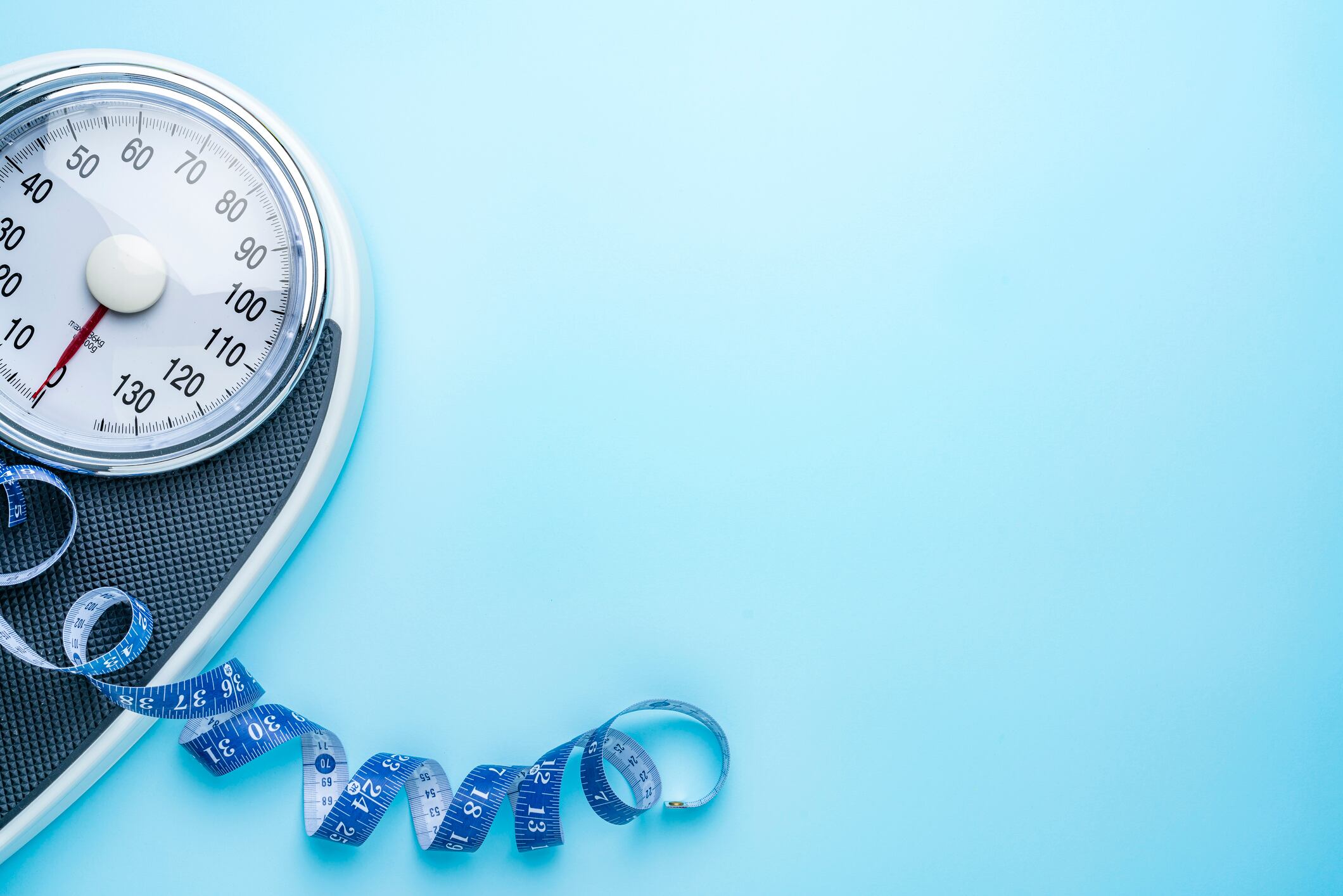 Weight scale and measuring tape on blue background. Flat lay with copy space