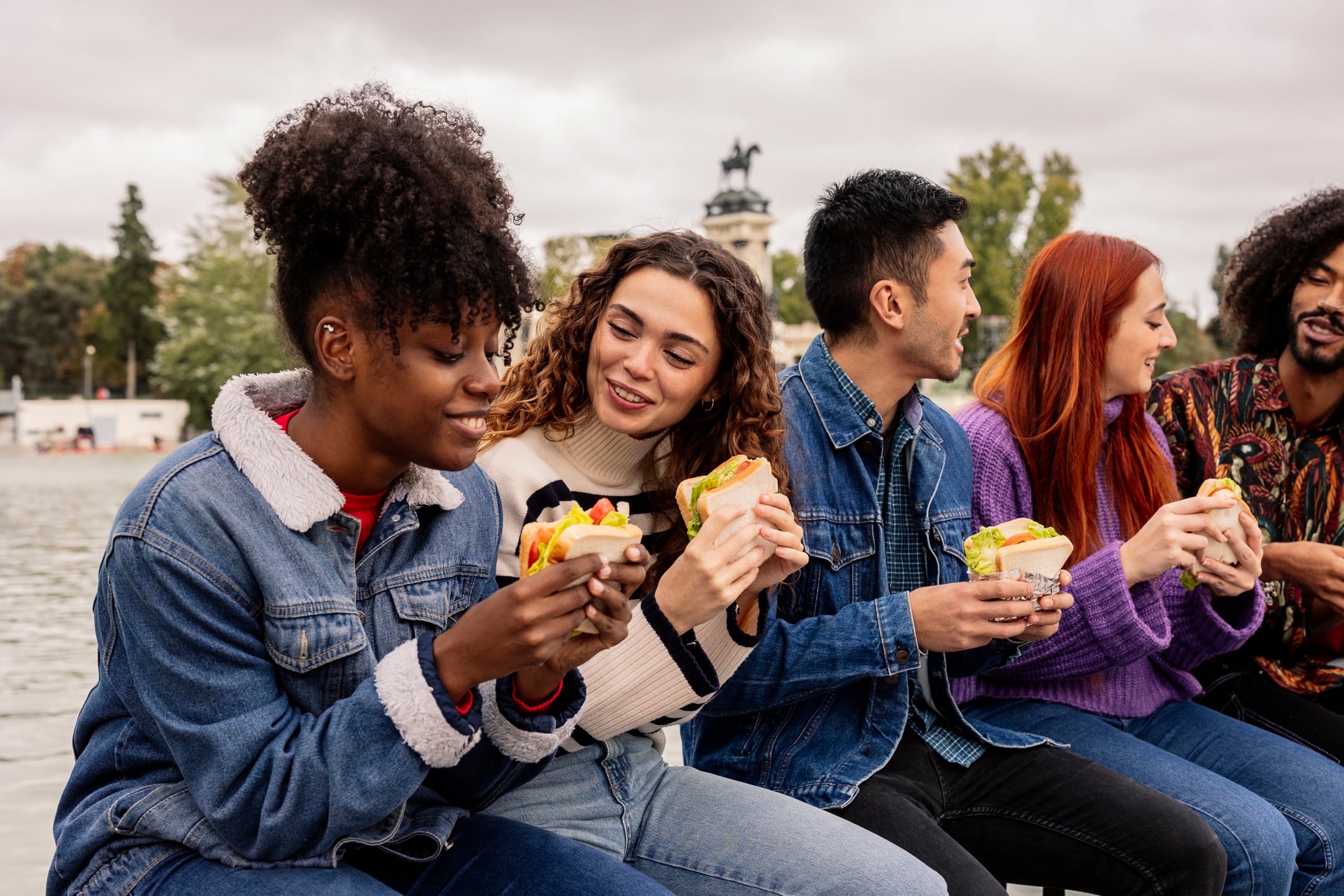 Multicultural friends on university break eating a sandwich while laughing Jose carlos Cerdeno GettyImages-1901777243.jpg