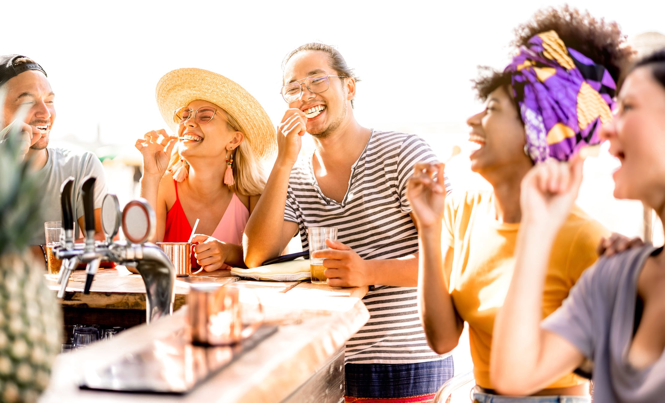Multiracial trendy friends having fun drinking bear at sunset beach party ViewApart GettyImages