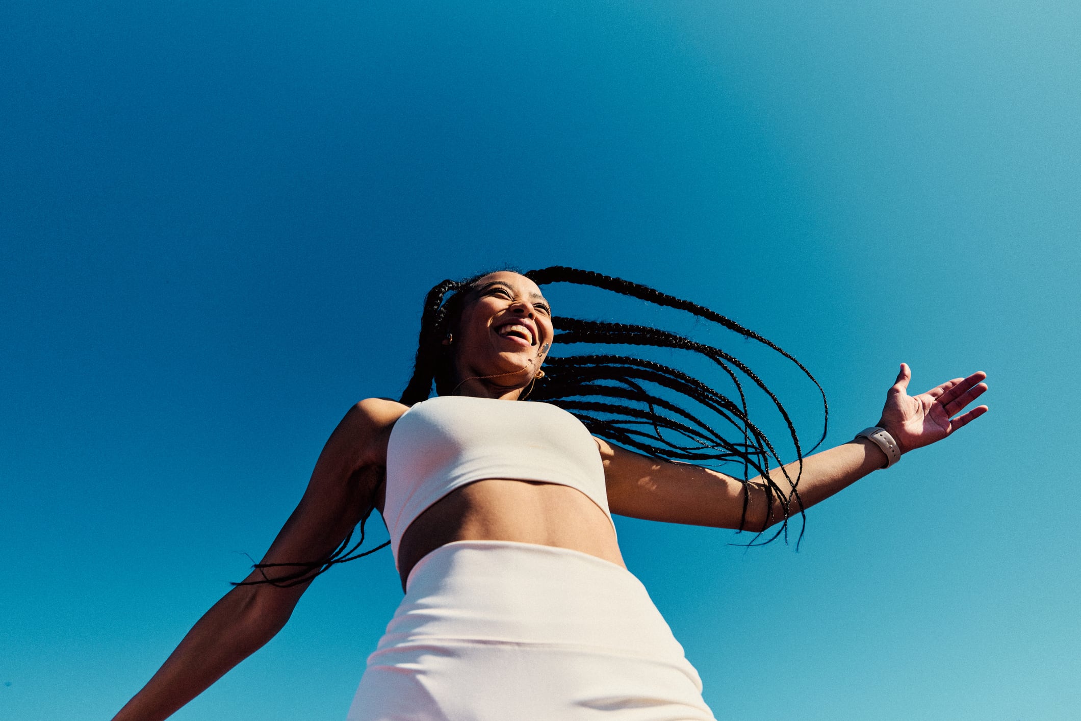 Attractive athletic woman wearing white sports clothing with arm out, view from below