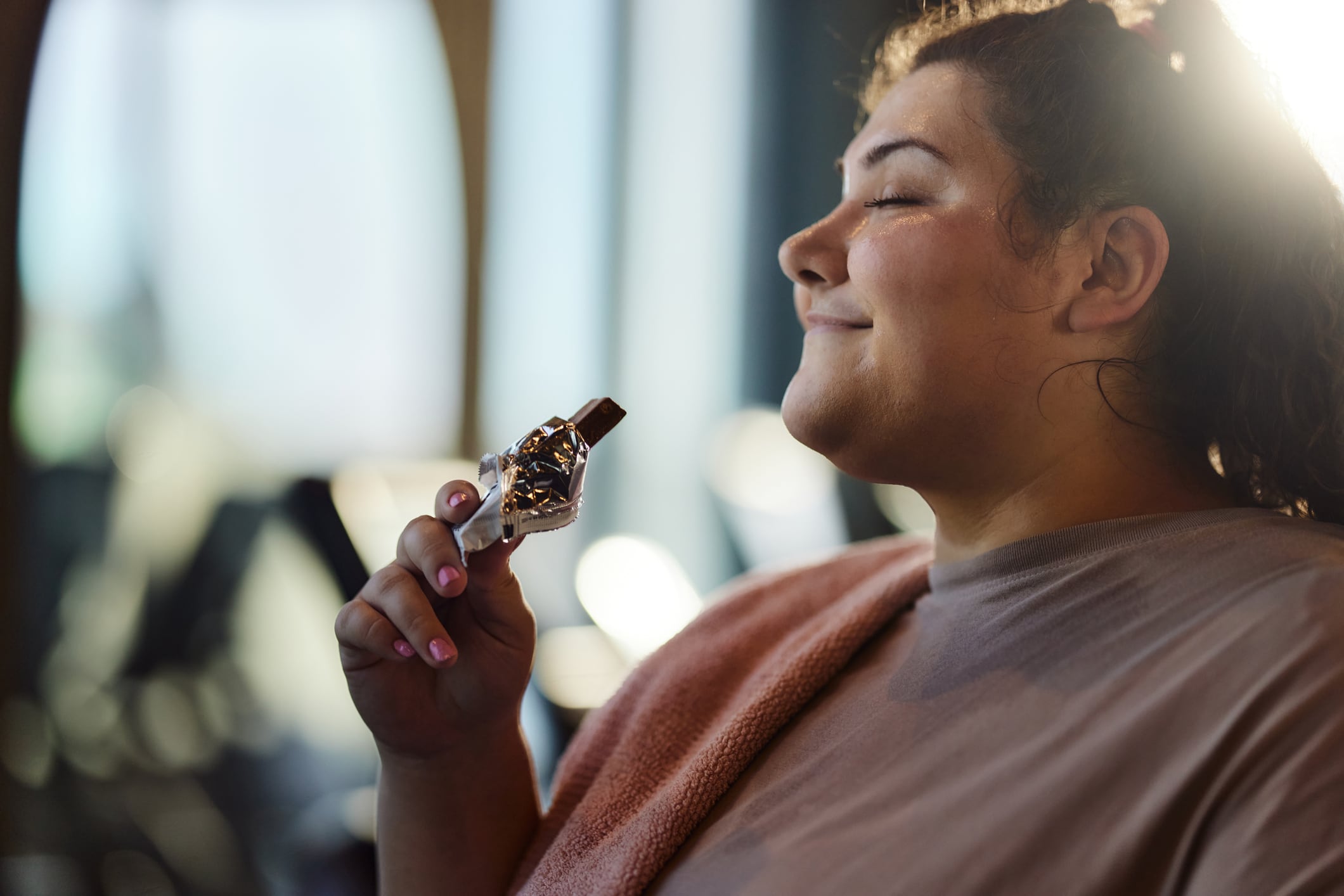 Functional foods for weight loss? Modified collagen helps people lose weight, without the side effects of GLP-1 drugs. Image: Smiling obese woman enjoying while eating protein bar in a gym.