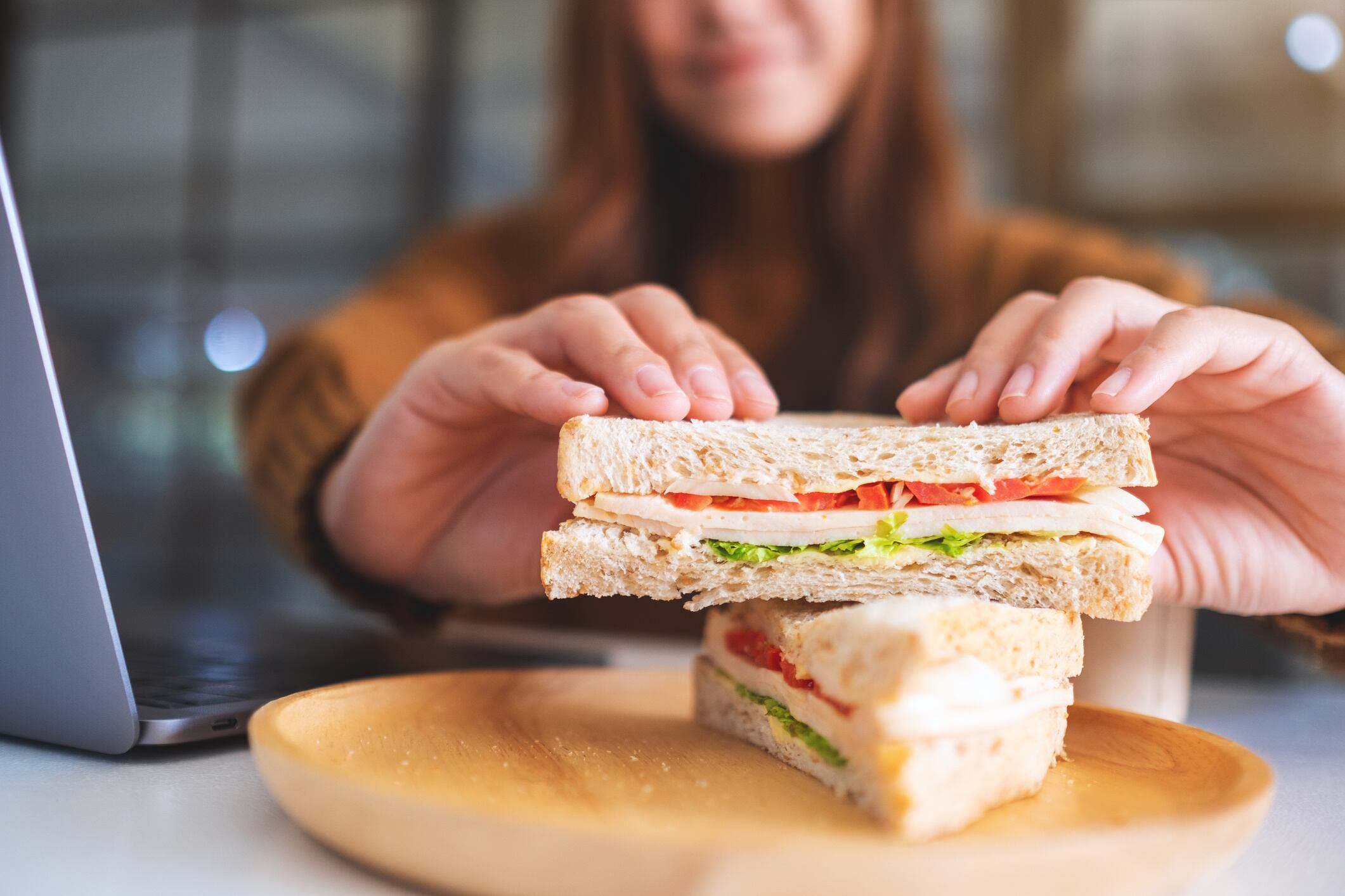 Young woman at her desk picking up a sandwich