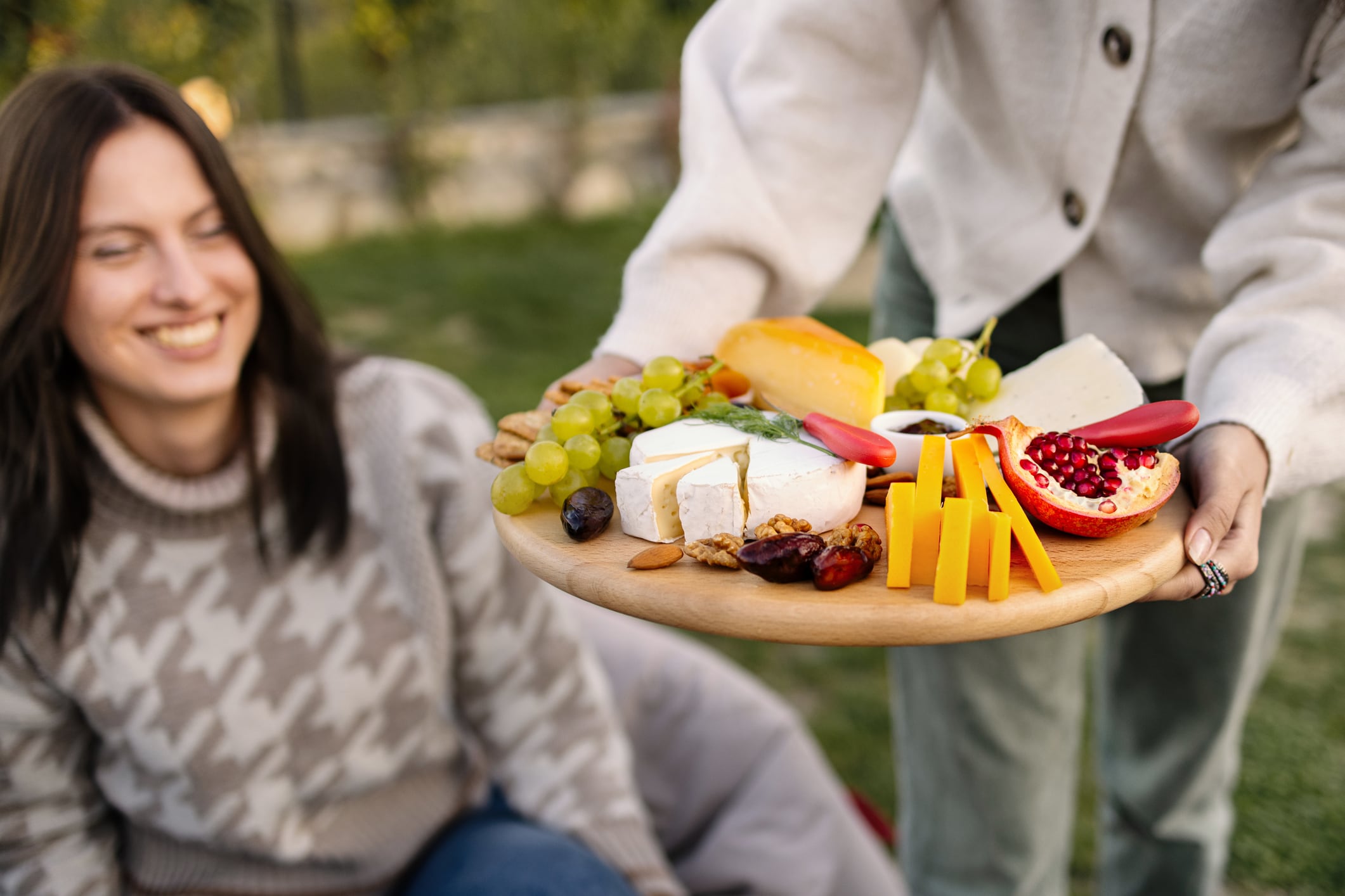 Female bringing cheese board at a picnic gathering with friends.